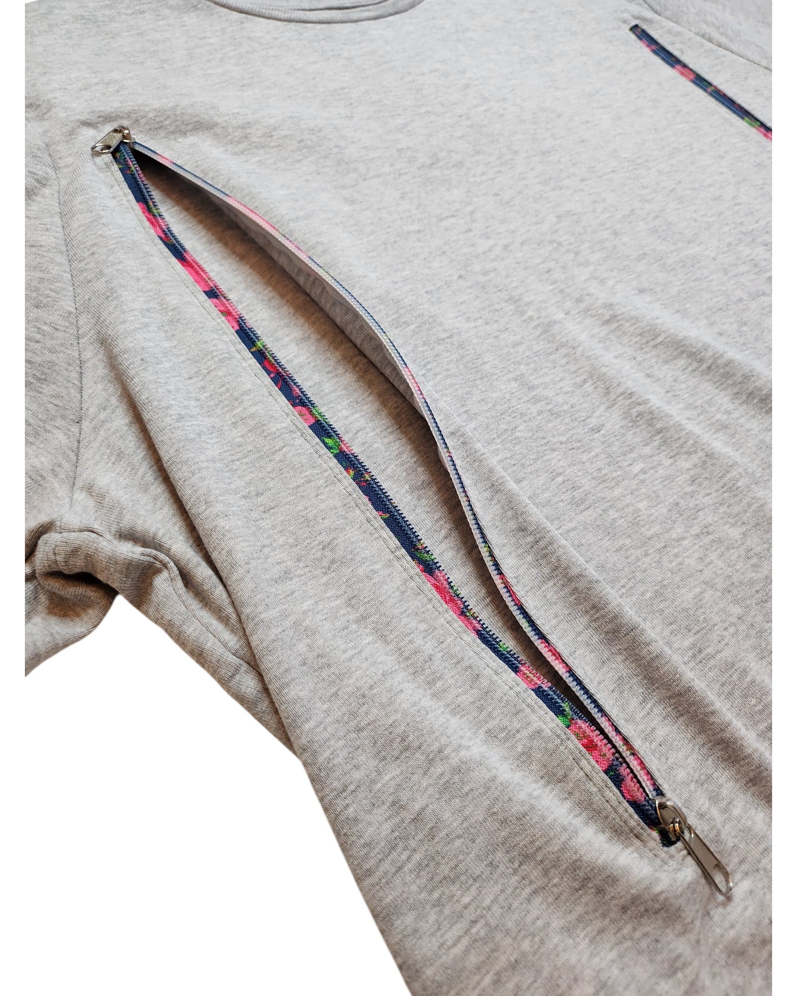 The touched out mama Upcycled Breastfeeding Grey Floral Zips T-shirt (UK24) has a diagonal zipper from sleeve to mid-torso, ideal for nursing. Its soft fabric and relaxed fit make it a perfect choice.