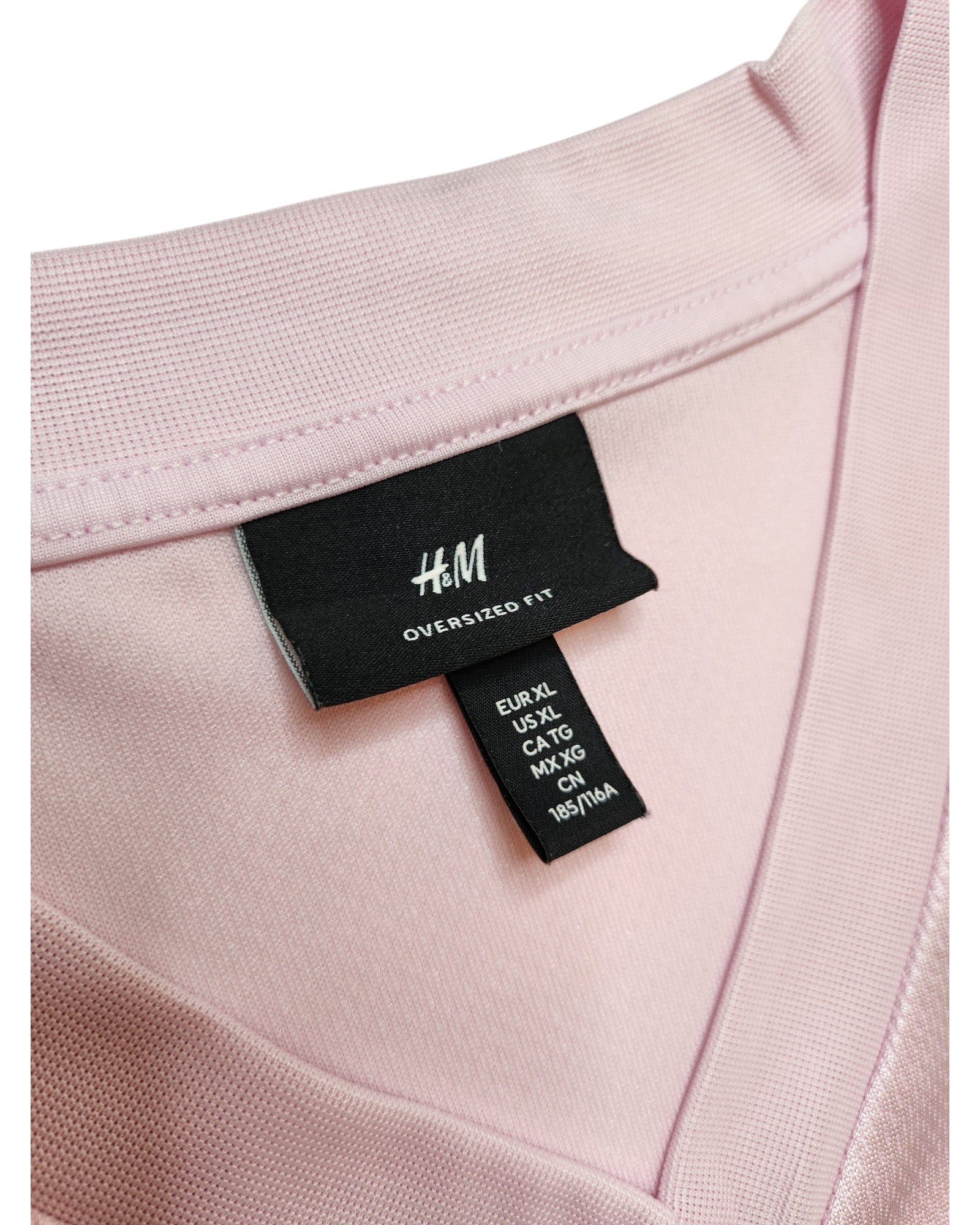 Close-up of an H&M Upcycled Breastfeeding (Nursing) & Pumping Football Jersey XL in light pink, showing the collar and labels. Oversized fit makes it ideal for nursing, pumping, or anyone wanting comfy, eco-friendly clothing.