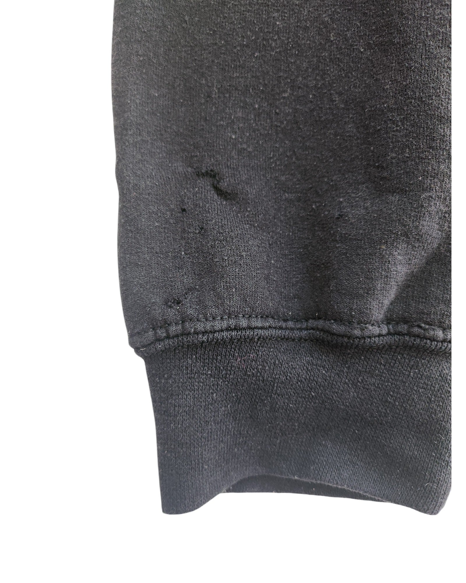 The close-up shows a distressed black fabric sleeve of the Upcycled Breastfeeding & Pumping Little Mix Hoodie L by touched out mama, featuring visible small holes and worn areas near the seam. Prominent stitching gives it a slightly faded appearance, highlighting its upcycled clothing heritage against a plain white background.