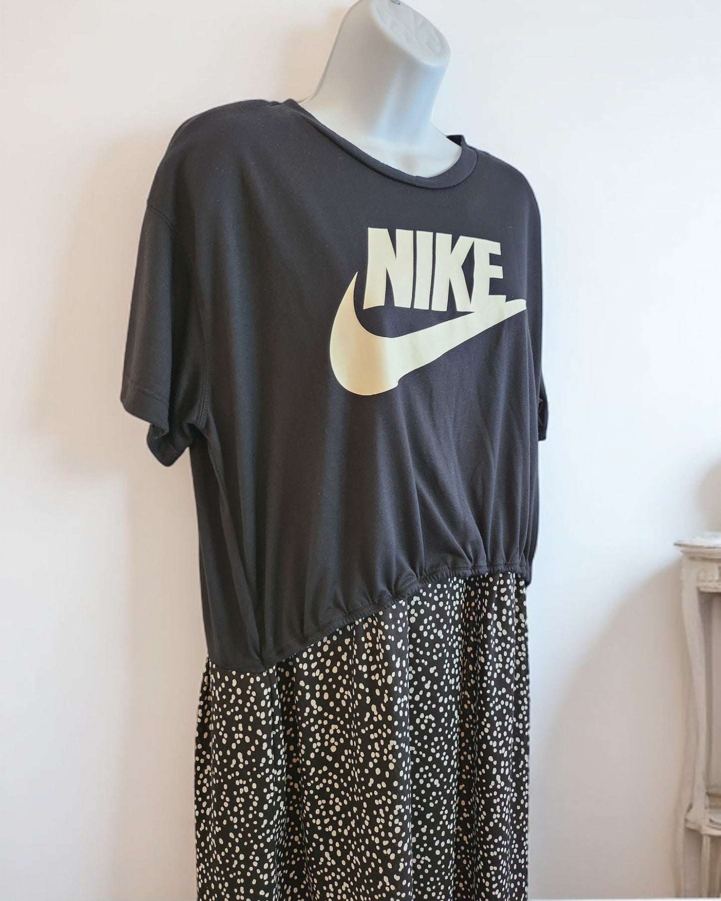 A mannequin displays the touched out mama Upcycled Breastfeeding & Pumping NIKE Maxi Dress, size M/L, with a black top featuring a white Nike logo and a chic black and white polka dot skirt. The waist transitions from casual tee to flowy skirt, merging sustainability with style.