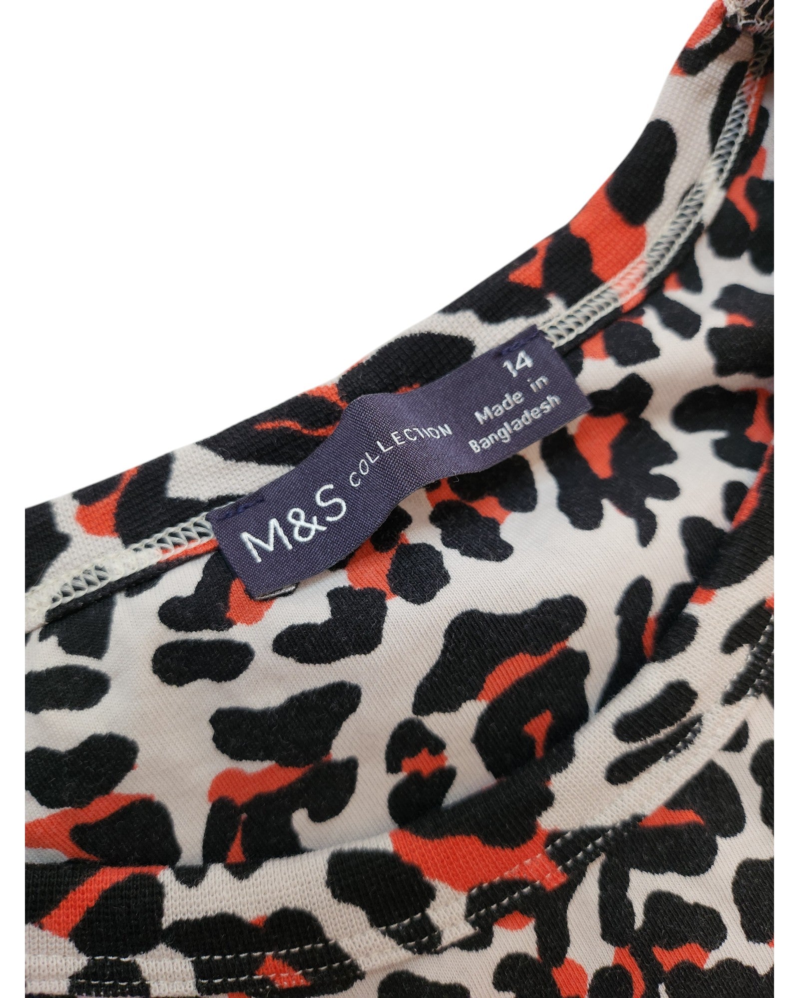 Close-up of a garments neckline showing a black and orange leopard print. Part of an eco-friendly line, the label reads touched out mama, Upcycled Breastfeeding (Nursing) & Pumping Leopard Pocket T-shirt Dress, UK14, carefully sewn into the fabric.