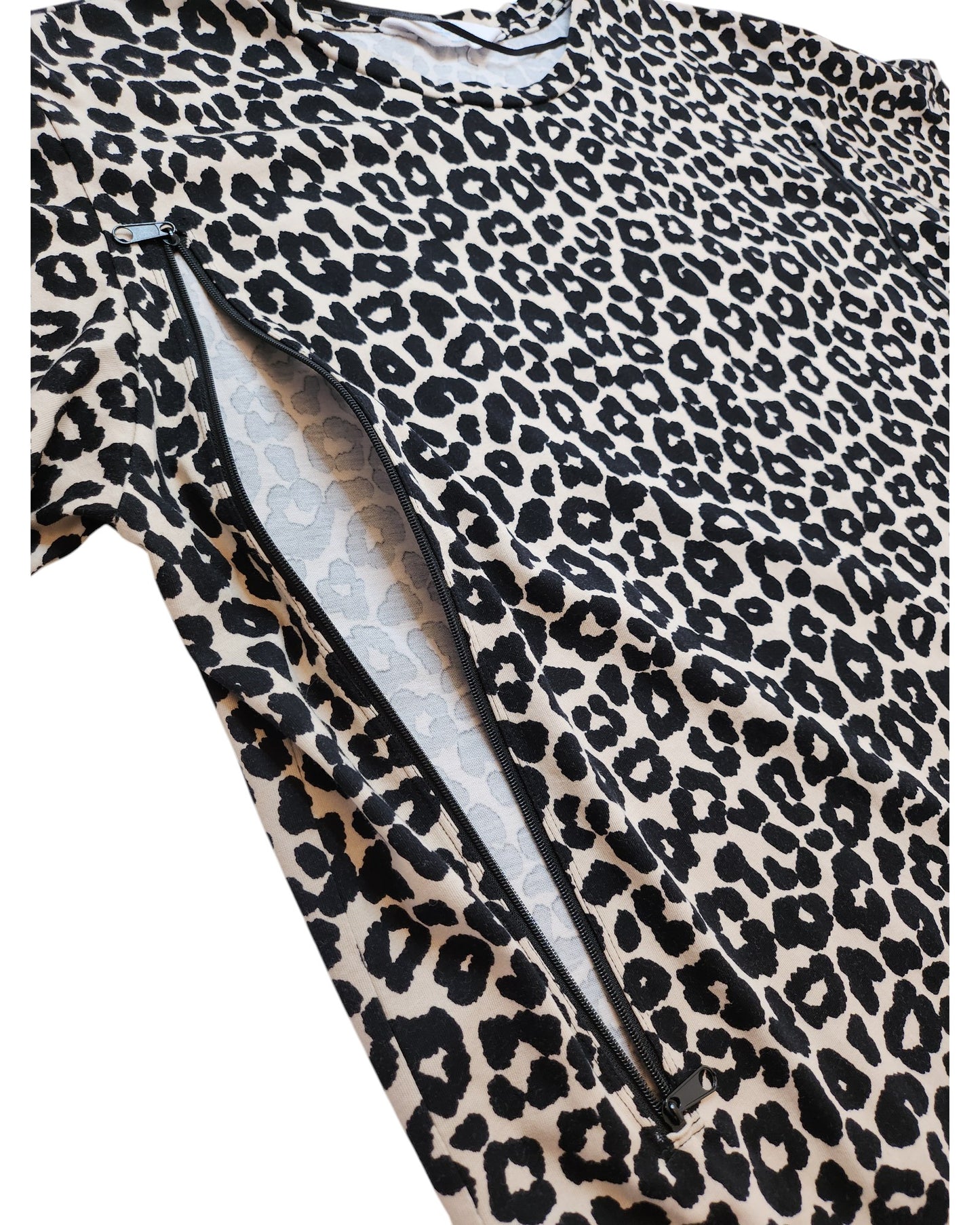 A partially opened zipper reveals lighter fabric beneath a bold, eco-friendly, upcycled leopard print t-shirt by touched out mama. The black spots on the white background make this nursing & pumping wear (size M) a fashionable statement.