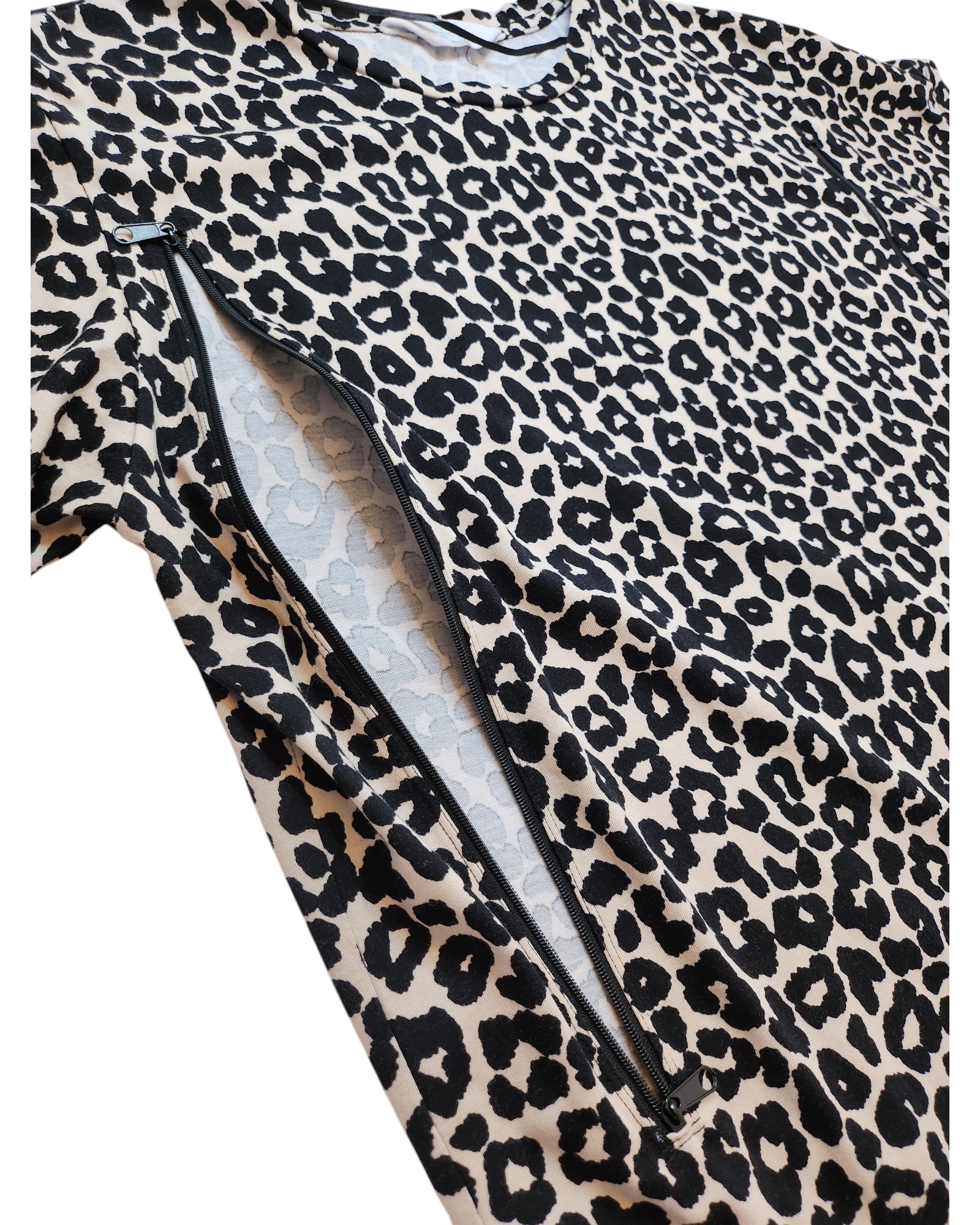 A partially opened zipper reveals lighter fabric beneath a bold, eco-friendly, upcycled leopard print t-shirt by touched out mama. The black spots on the white background make this nursing & pumping wear (size M) a fashionable statement.