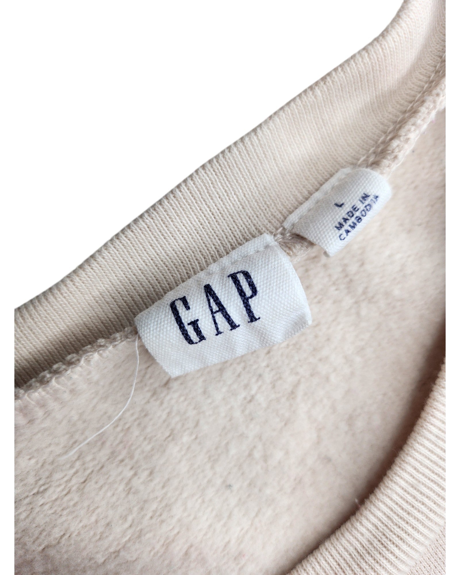Close-up of the neck tag on a beige sweatshirt by touched out mama, with GAP in navy letters. Beneath it, a label reads L MADE IN CAMBODIA. This preloved, upcycled breastfeeding and pumping GAP sweatshirt has a soft, fleece-like texture.