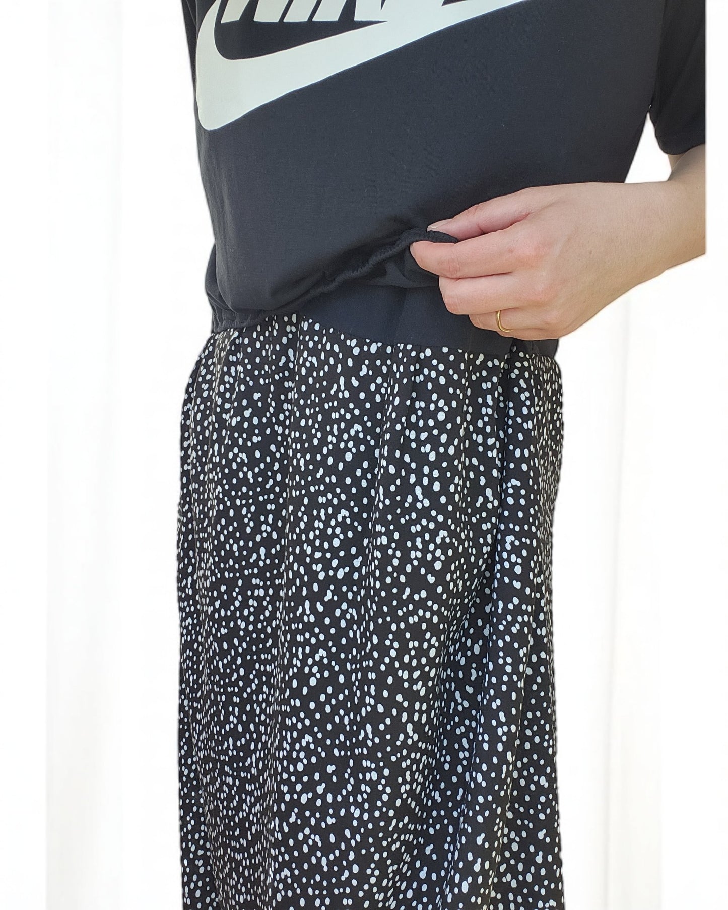 A person dressed in touched out mamas Upcycled Breastfeeding & Pumping NIKE Maxi Dress M/L stands gracefully, hand on waist, against a light background.