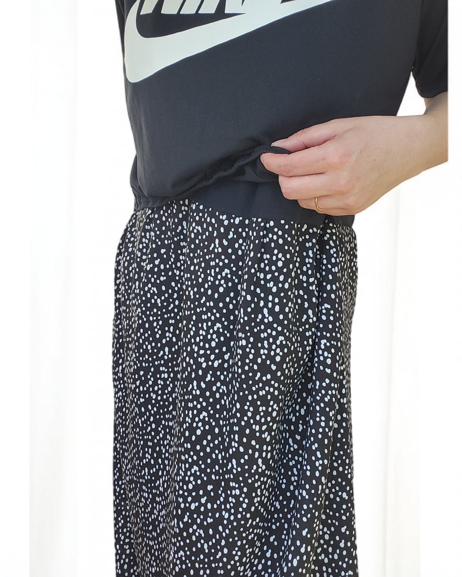 A person dressed in touched out mamas Upcycled Breastfeeding & Pumping NIKE Maxi Dress M/L stands gracefully, hand on waist, against a light background.