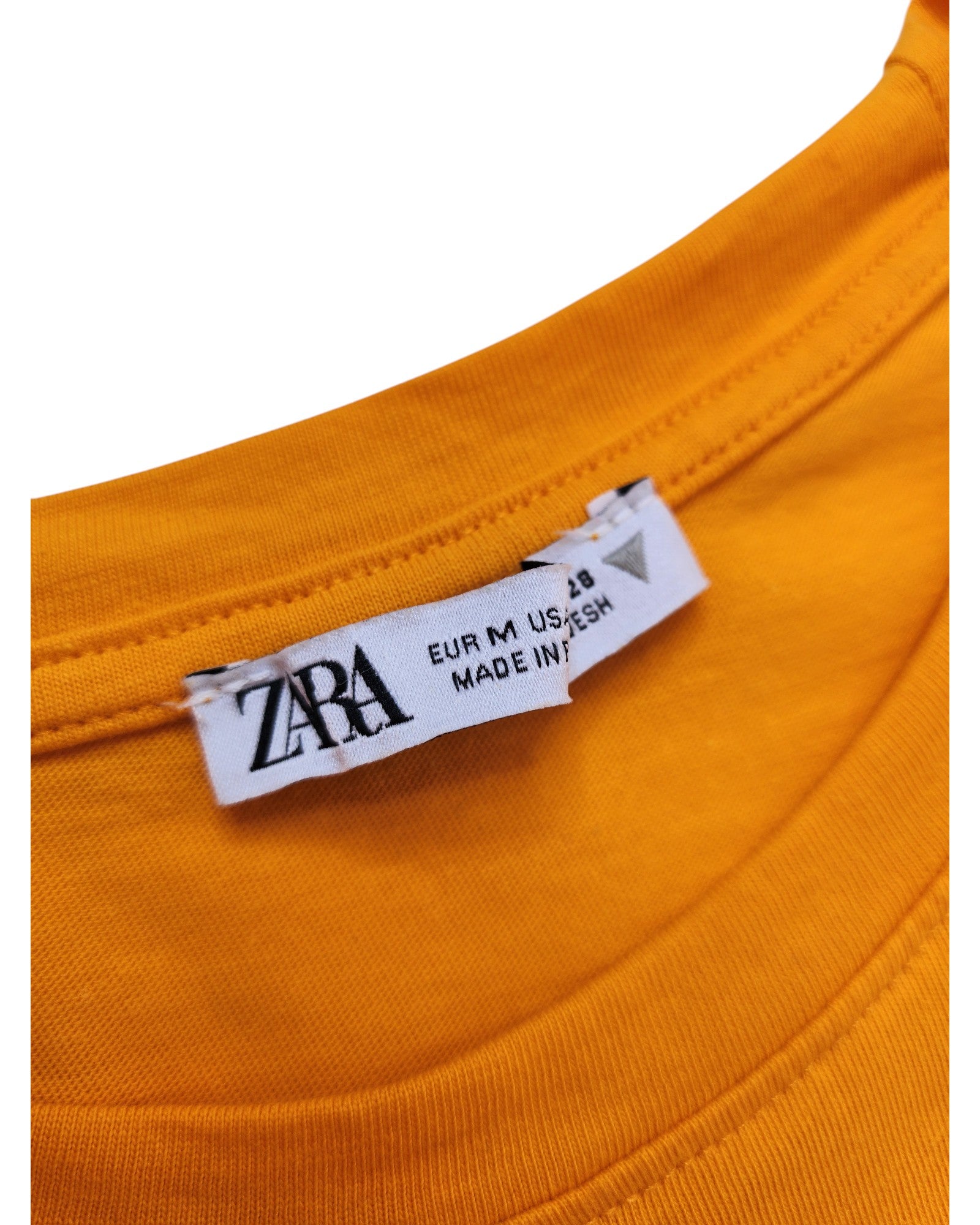 Close-up of a yellow t-shirts neck label showcasing touched out mama and indicating size EUR M / USA S / MEX 28. Expertly crafted in eco-friendly materials, this Upcycled Breastfeeding & Pumping Plain Frill Zara t-shirt represents a step forward in sustainable fashion.