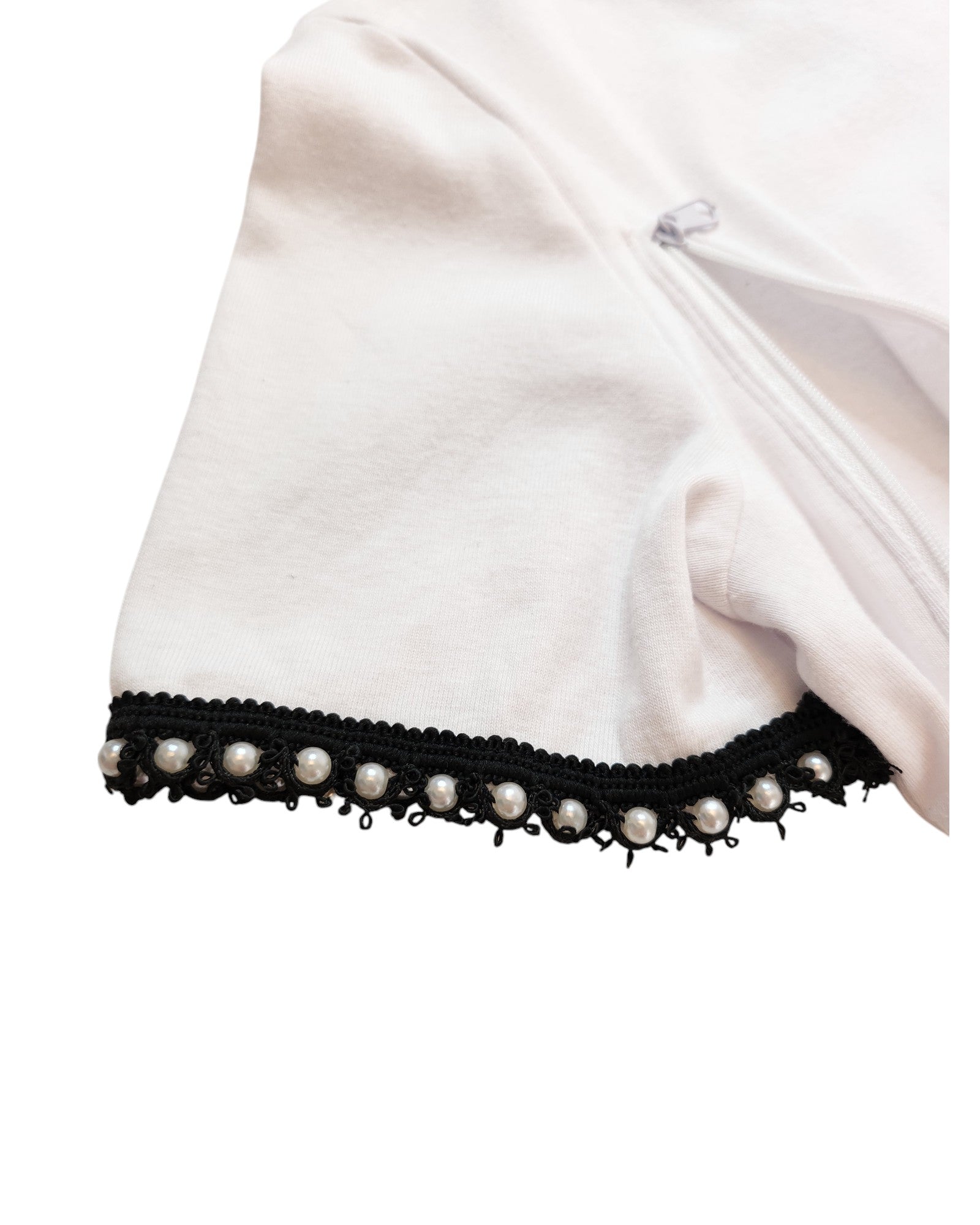 Close-up of a white sleeve from the Upcycled Breastfeeding & Pumping Plain White ZARA T-shirt M by touched out mama, featuring decorative black trim with small pearls and a vertical zipper. The eco-friendly fabric is soft and slightly wrinkled.