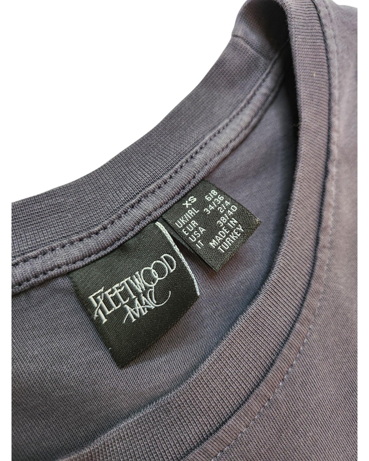 Close-up of an Upcycled Breastfeeding & Pumping Fleetwood Mac Floral t-shirt (XS) by touched out mama, featuring collar tags with the band’s logo and care info—spotlighting this unique preloved piece.