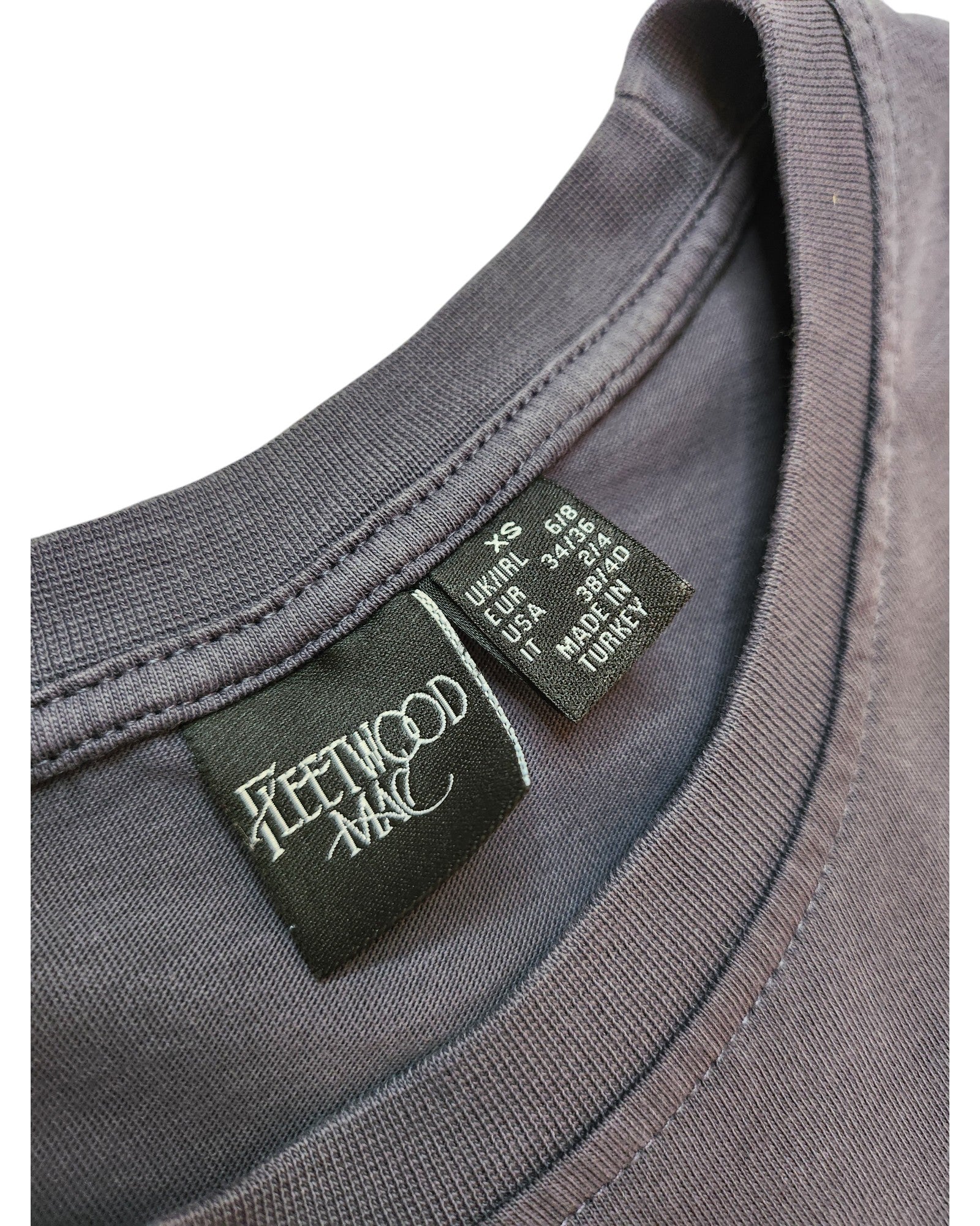 Close-up of an Upcycled Breastfeeding & Pumping Fleetwood Mac Floral t-shirt (XS) by touched out mama, featuring collar tags with the band’s logo and care info—spotlighting this unique preloved piece.
