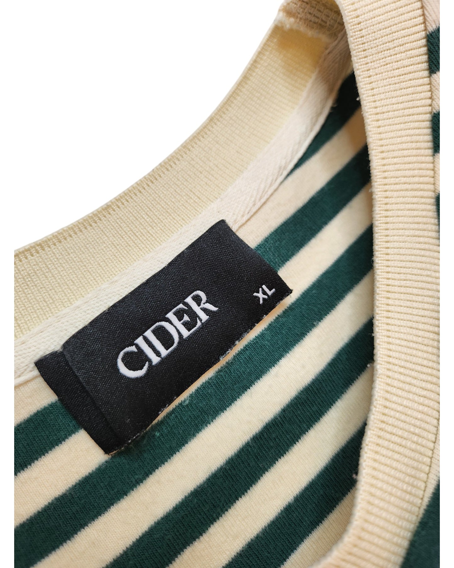 Close-up of the Upcycled Breastfeeding & Pumping Green Stripe T-shirt by touched out mama, size XL. It exemplifies sustainable fashion with green and cream hues. The brand label is sewn into the inside collar on a black background with white text.