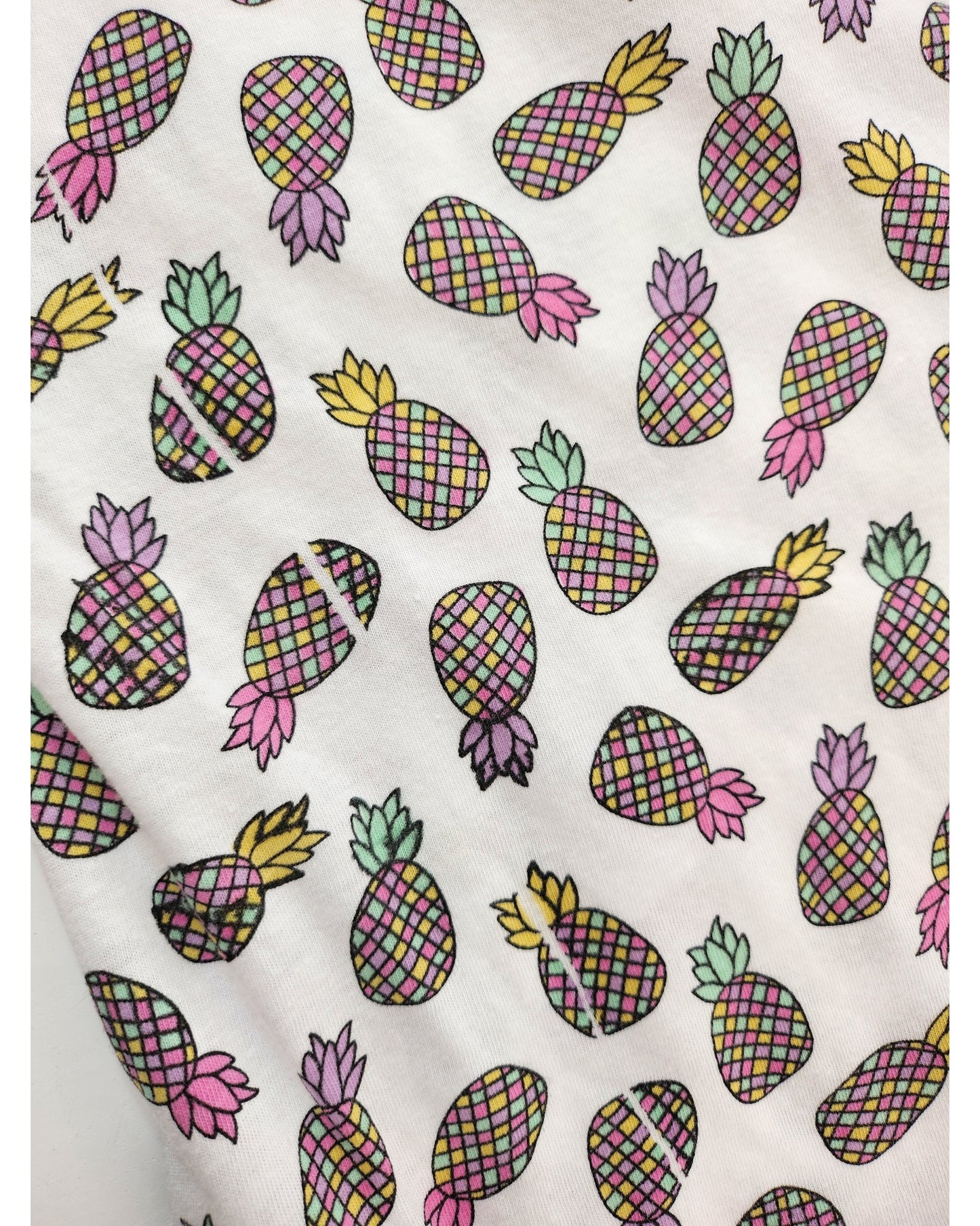 The Upcycled Breastfeeding & Pumping Pineapple t-shirt (UK20) by Primark is a white tee with colorful, checkered pineapples in various directions—made from preloved clothing for an eco-friendly choice.