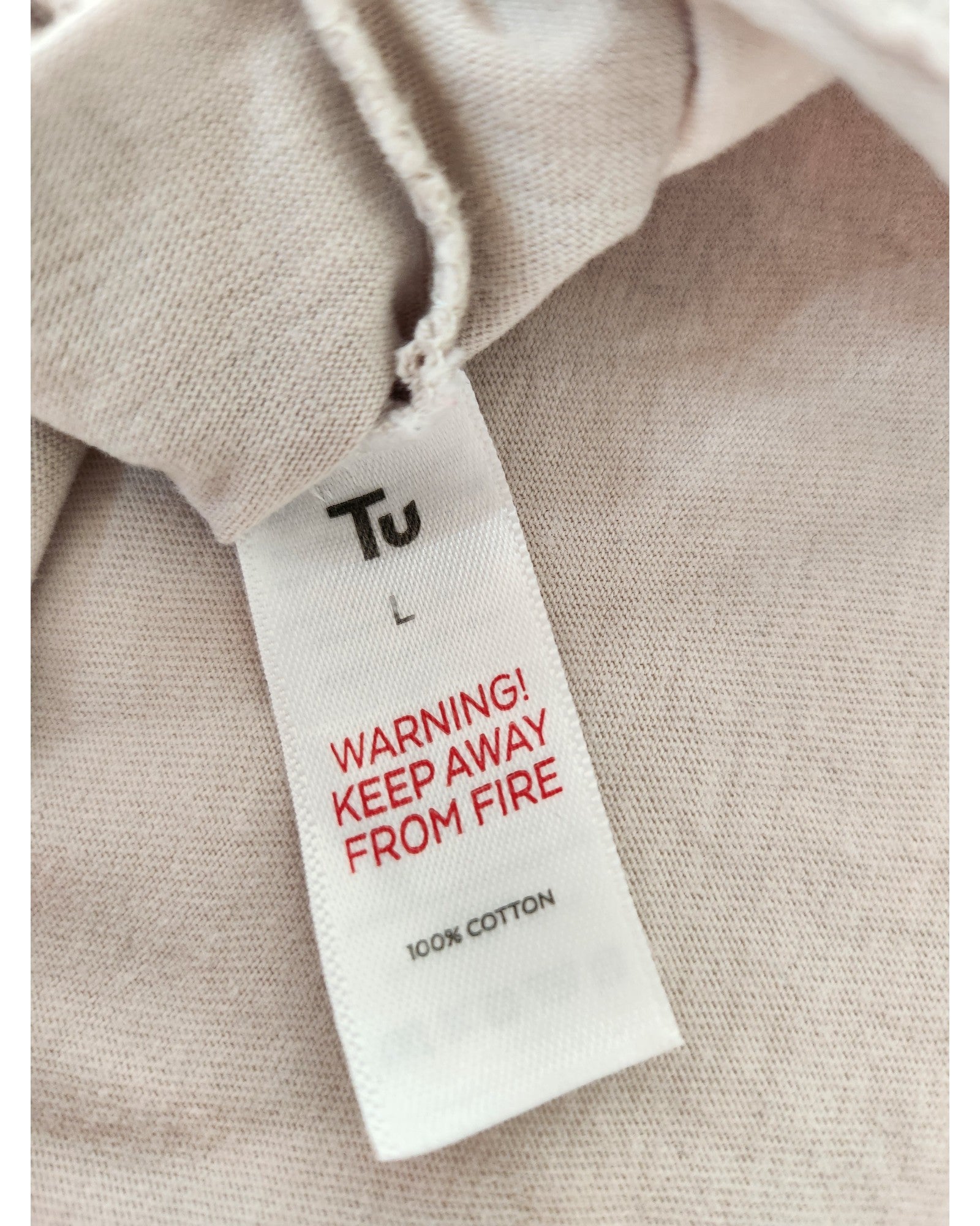 A close-up of the Tu label on the Upcycled Breastfeeding (Nursing) & Pumping Witch Dog t-shirt Nightdress L shows WARNING! KEEP AWAY FROM FIRE in red and 100% COTTON on light beige fabric.