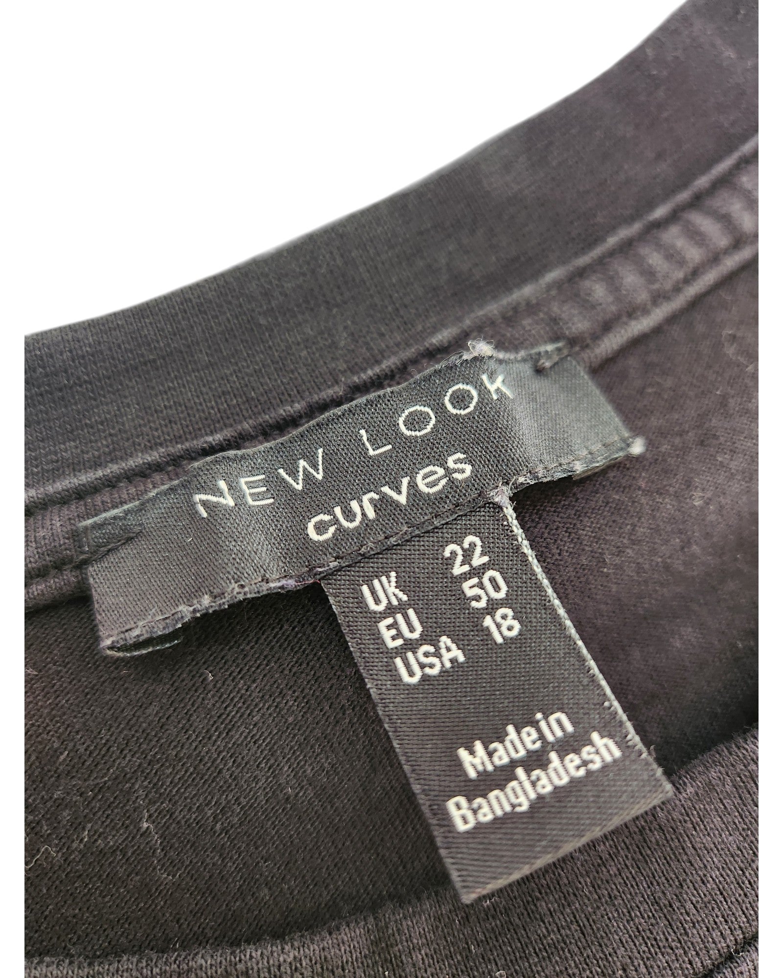 A close-up of a black clothing label stitched into a preloved Upcycled Breastfeeding & Pumping Plain Black Midi t-shirt dress UK22 by New Look, showing sizes UK 22, EU 50, USA 18, and Made in Bangladesh.