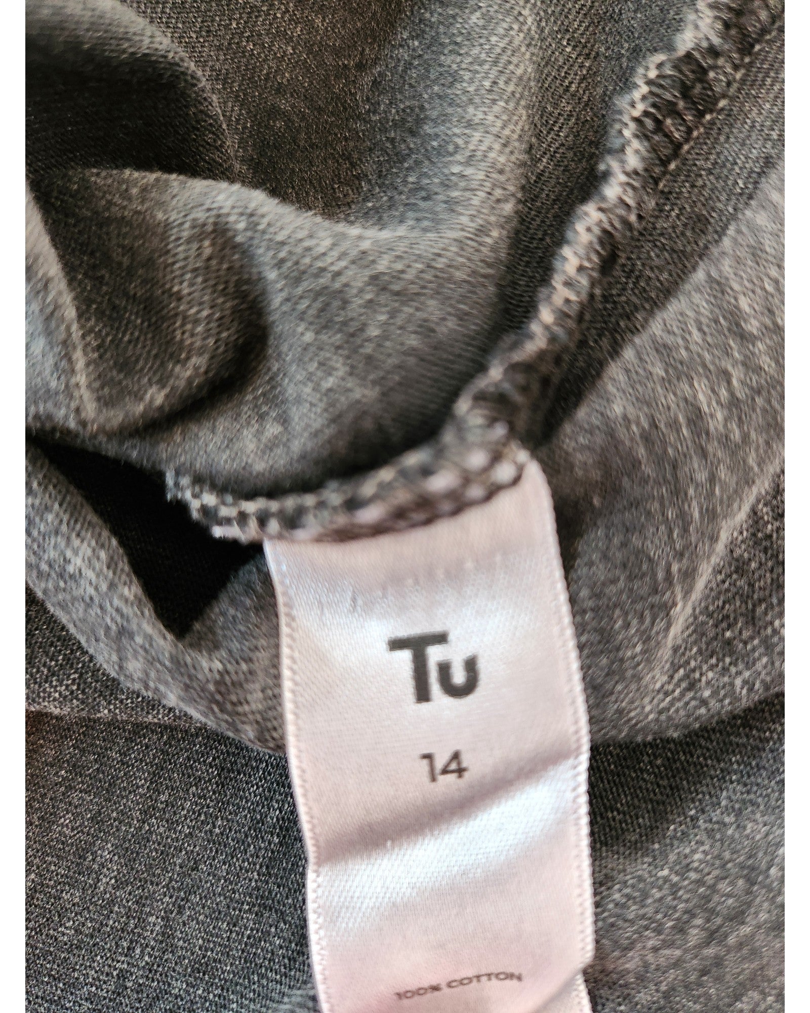 A close-up of the Tu label on an upcycled The Rolling Stones breastfeeding & pumping t-shirt (grey/brown, UK14). The soft, textured preloved fabric is perfect for conscious fashion lovers seeking both style and function.