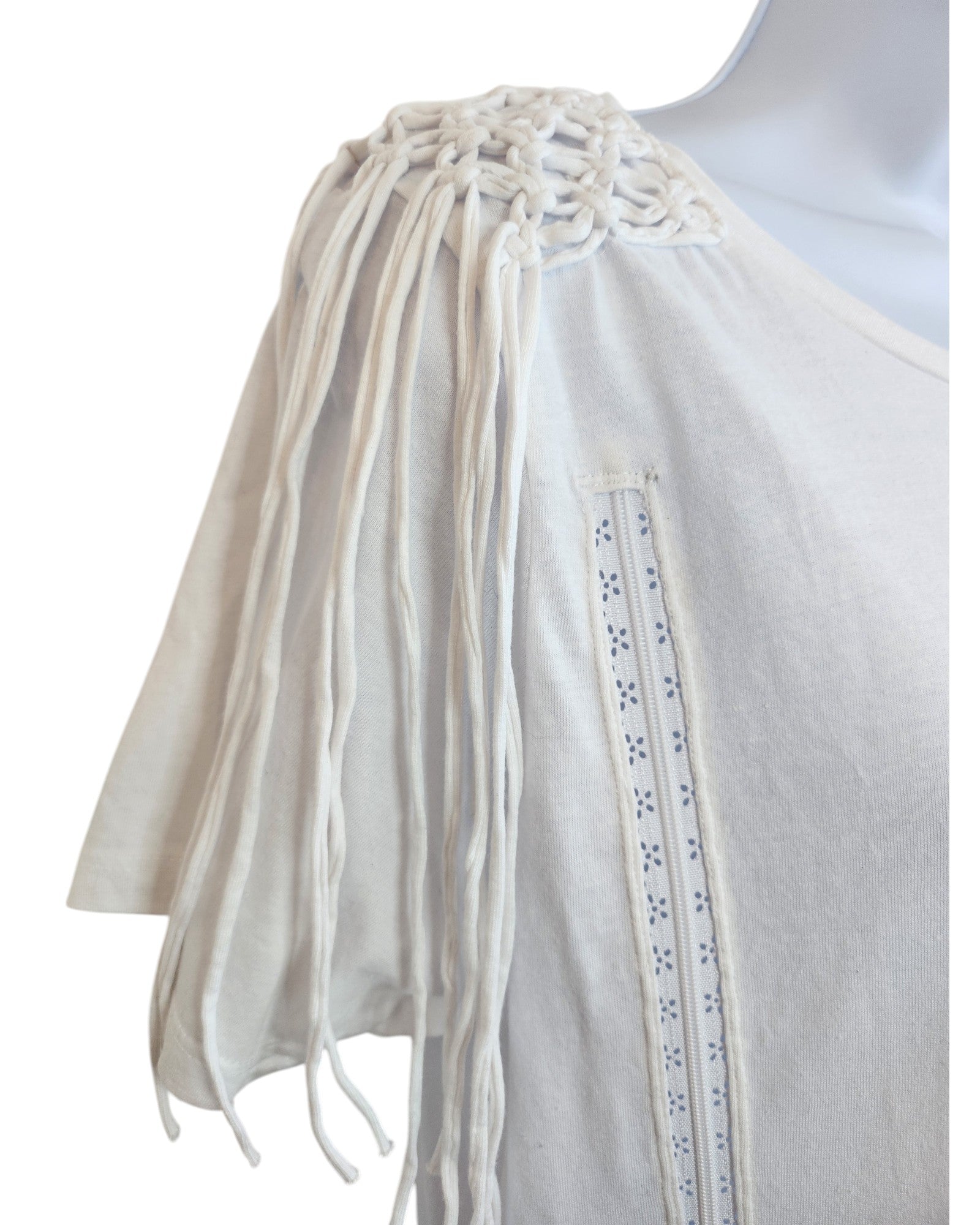 A close-up of the Pep & Co Upcycled Breastfeeding & Pumping Plain White Shoulder Fringing t-shirt UK12, featuring eco-friendly braided macramé fringing with long tassels and decorative eyelet trim on the front.