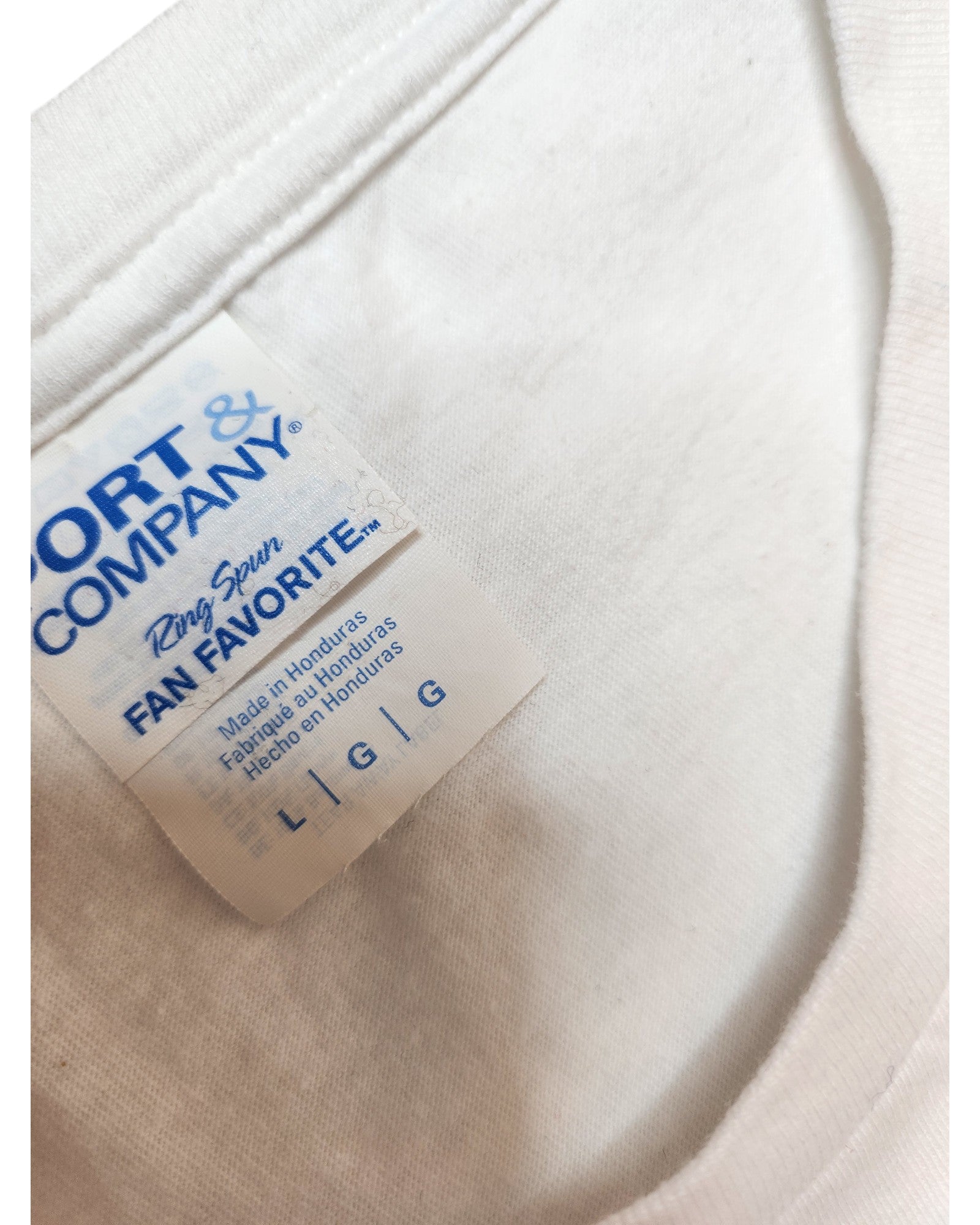 Close-up of a white Upcycled Breastfeeding & Pumping Little Miss Trouble T-shirt, size L from Port & Company, featuring an eco-friendly design and a neckline tag.