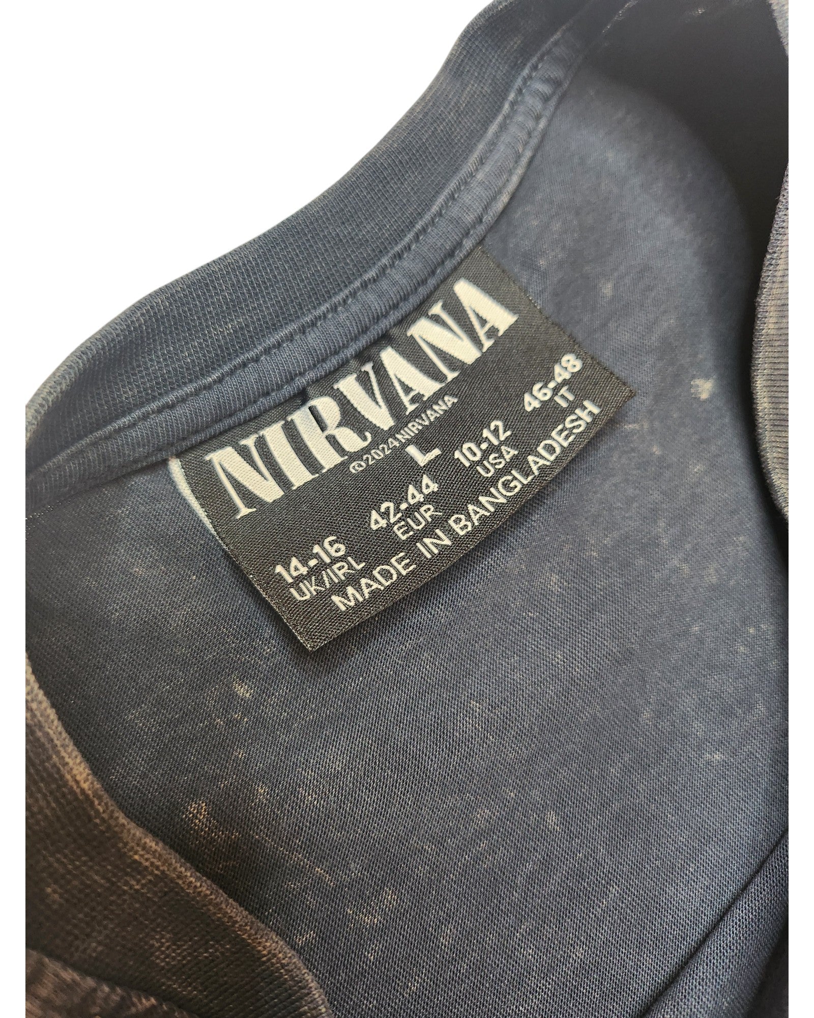 Close-up of a Primark upcycled grey/turquoise Nirvana Angel Band t-shirt (L, UK14/16), featuring a Nirvana label with size info and Made in Bangladesh text. Faded spots on the eco-friendly fabric add vintage character, ideal for nursing and pumping.