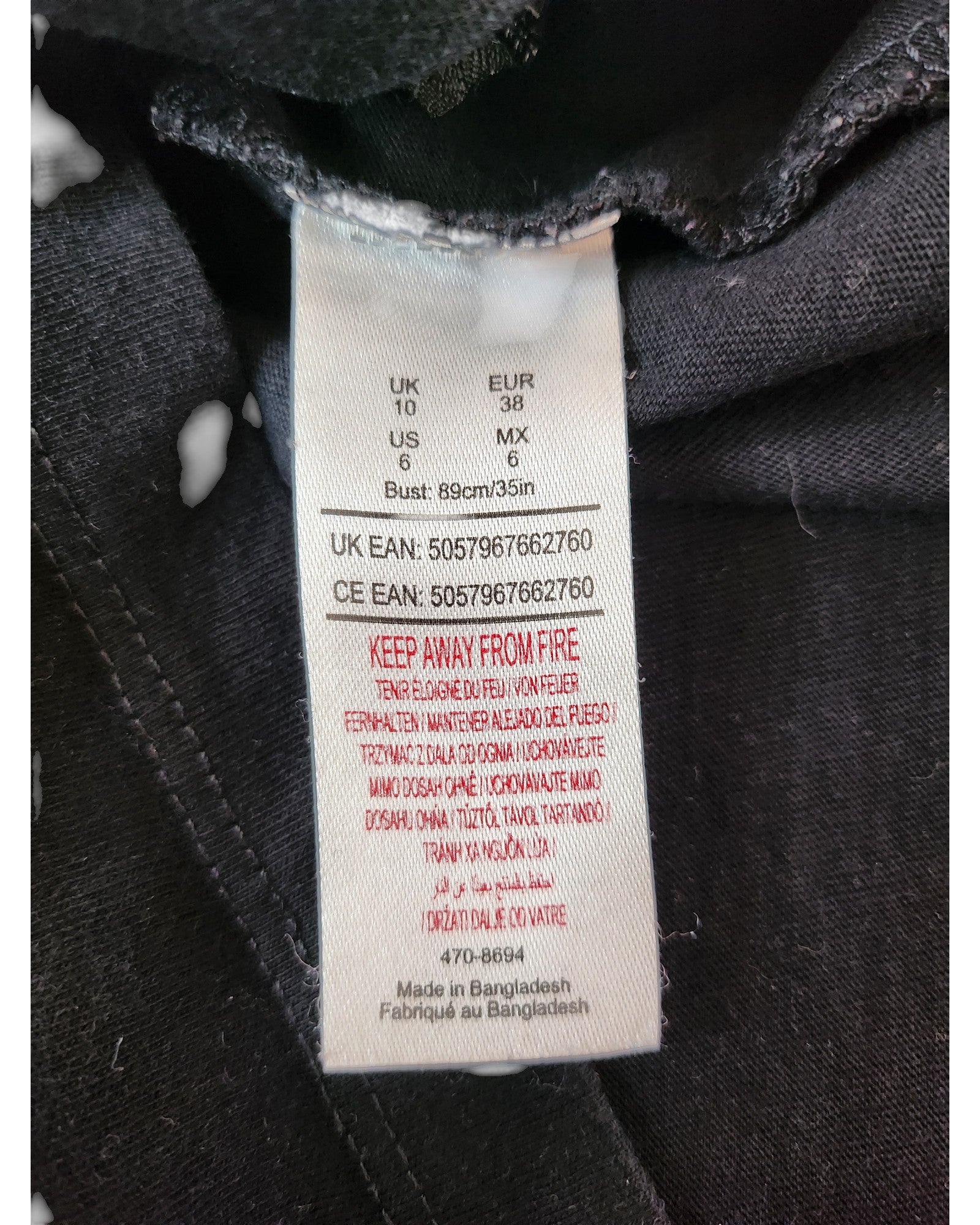 A close-up of the Summer of Rock Upcycled Breastfeeding & Pumping The Beatles t-shirt (UK10) label sewn into black fabric shows multi-region sizes, care instructions, a red fire warning, and notes eco-friendly production in Bangladesh.