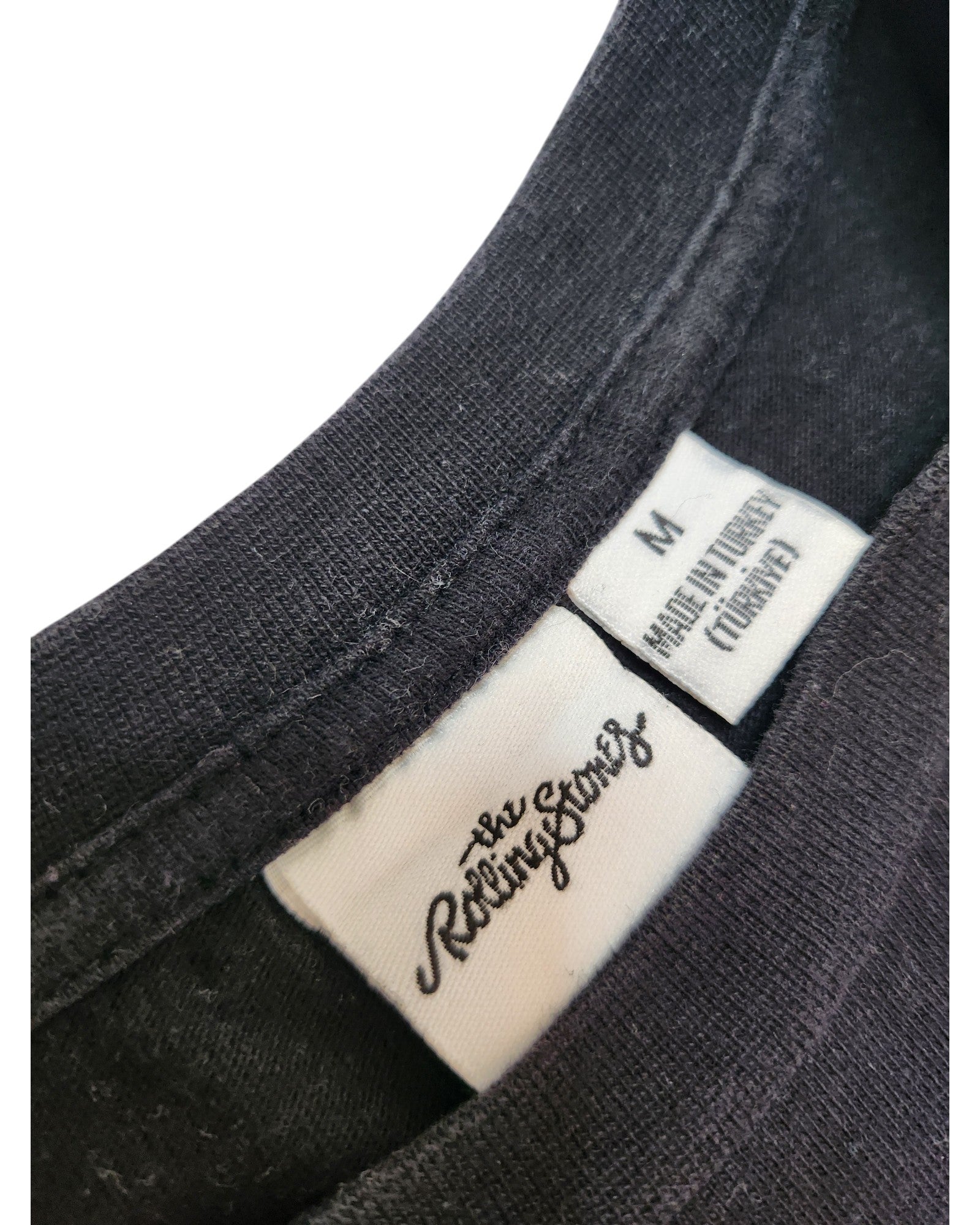 Close-up of the neckline and tags on this upcycled Primark The Rolling Stones Band nursing & pumping t-shirt (size M), featuring brand logos, size info, and Made in Turkey—perfect for fans of preloved fashion.