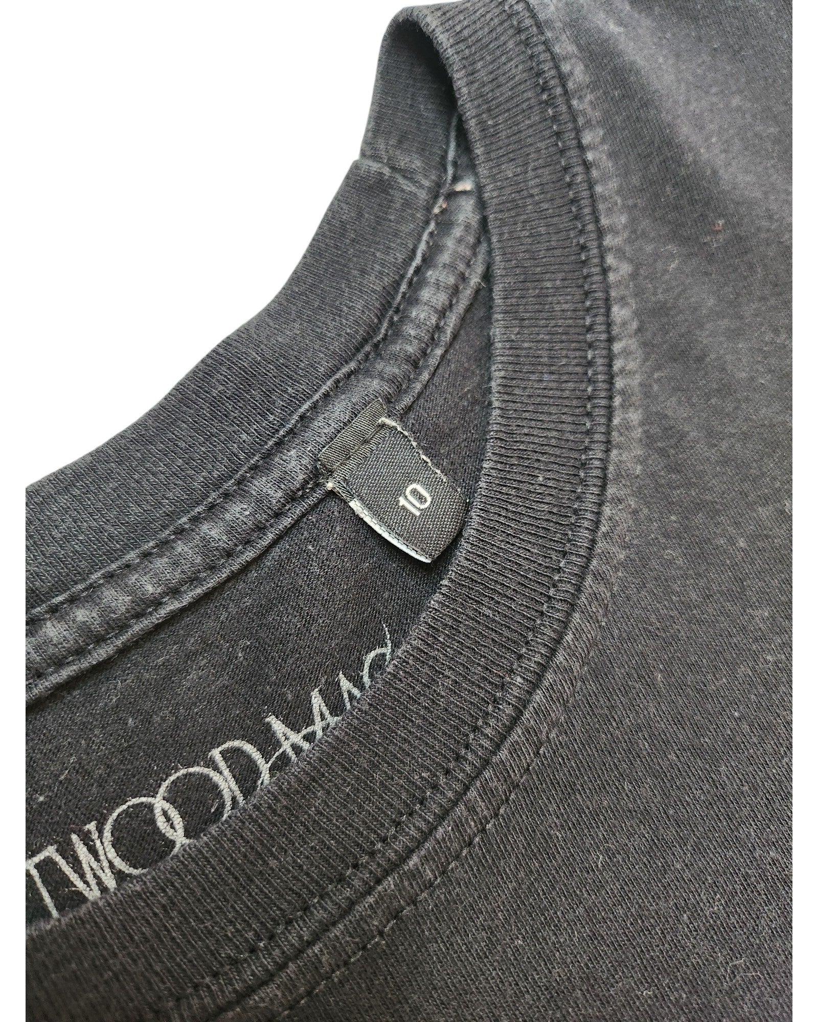 Close-up of a black Fleetwood Mac Rumours UK10 t-shirt collar with a size tag and partially visible white inner text, showcasing its upcycled, eco-friendly materials for breastfeeding and pumping.