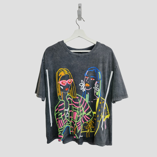The ZARA Upcycled Breastfeeding & Pumping Grey Girl Outlines T-shirt (size L) features a colorful neon-style graphic of two women with sunglasses and large earrings, hanging on a white hanger against a light background.