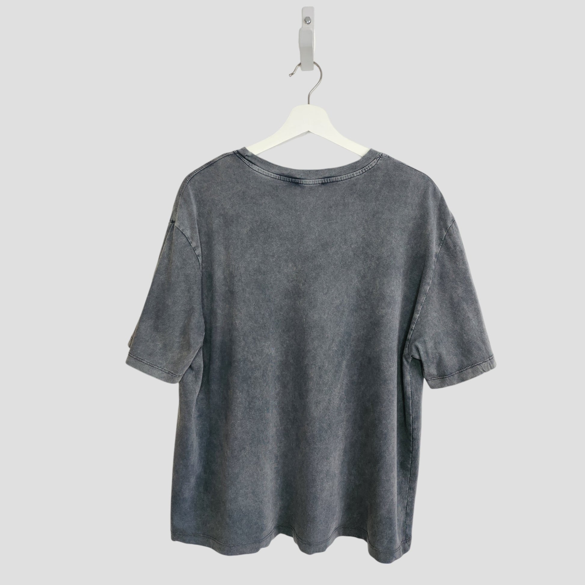 The Upcycled Breastfeeding & Pumping Grey ZARA Girl Outlines t-shirt (L) by ZARA hangs on a white hanger against a light gray background, shown from the back.