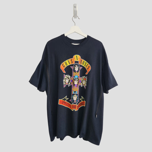 An upcycled black XXL GNR Nursing & Pumping T-shirt hangs on a white hanger, showcasing the Appetite for Destruction album cover with cartoon skulls in a cross and the bands bold yellow and red logo.
