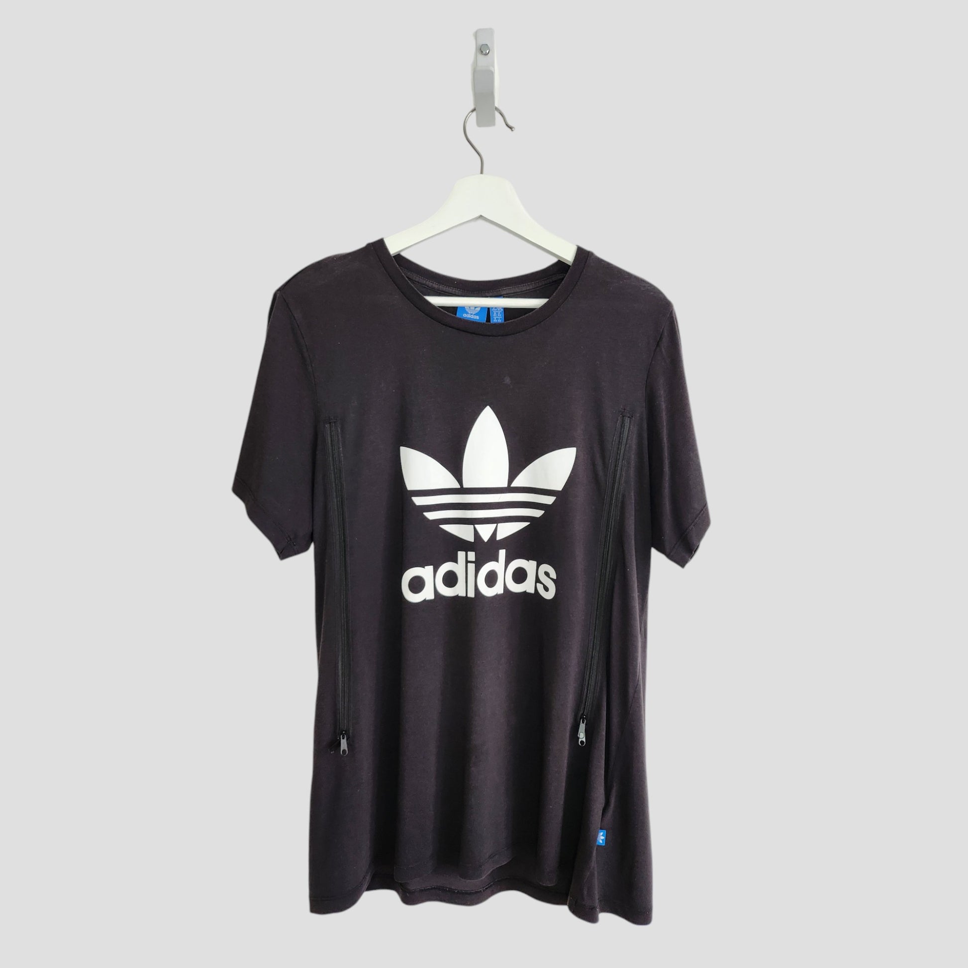 An upcycled Adidas black and white breastfeeding & pumping T-shirt (UK14) with trefoil logo and adidas text on the front, shown on a white hanger against a light gray background.