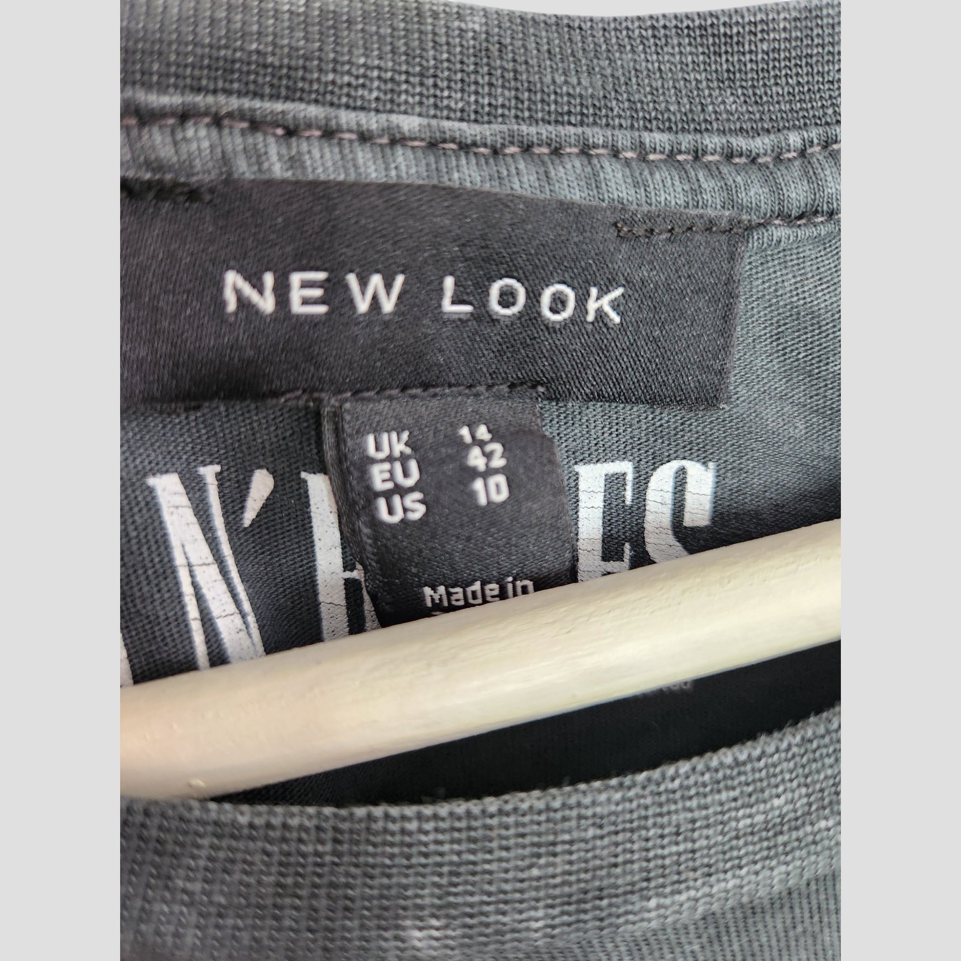 Close-up of a New Look clothing label on an upcycled breastfeeding & pumping grey Guns n Roses band t-shirt (UK14). Size tag: UK 14, EU 42, US 10. Wooden hanger visible—ideal for displaying preloved fashion.