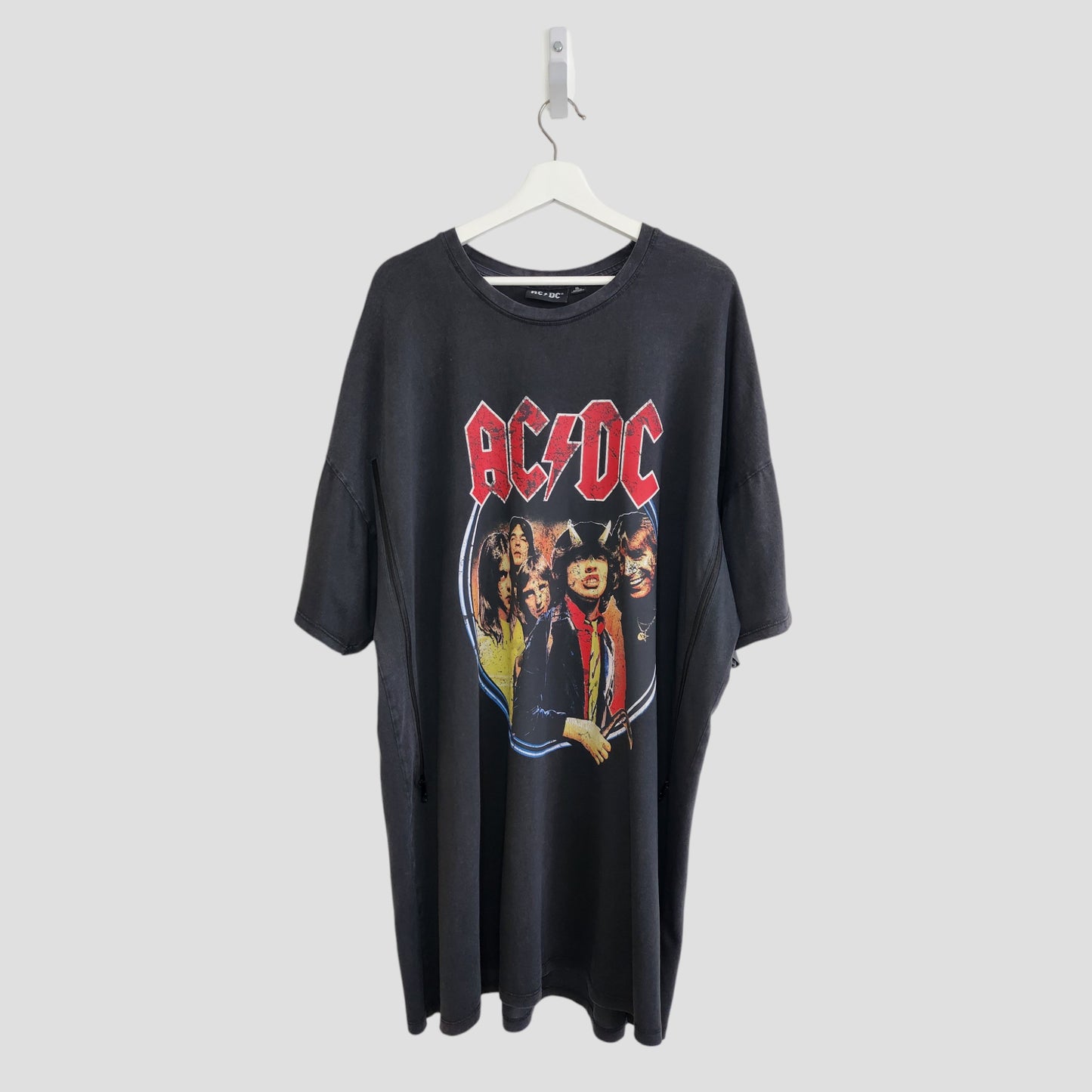 The Primark Upcycled Breastfeeding & Pumping AC/DC Faces t-shirt dress (XL, UK18/20) features a black oversized design with the red AC/DC logo and band image, displayed on a white hanger against a plain gray background.