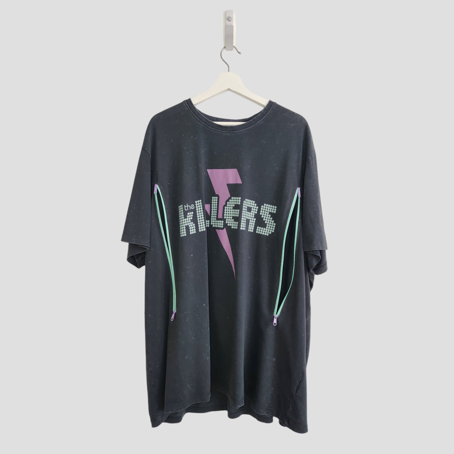 The Killers Upcycled Breastfeeding & Pumping Band T-shirt 3XL features a black oversized fit, dotted band name, pink lightning bolt, and two side zips—ideal for nursing moms or upcycled fashion fans.
