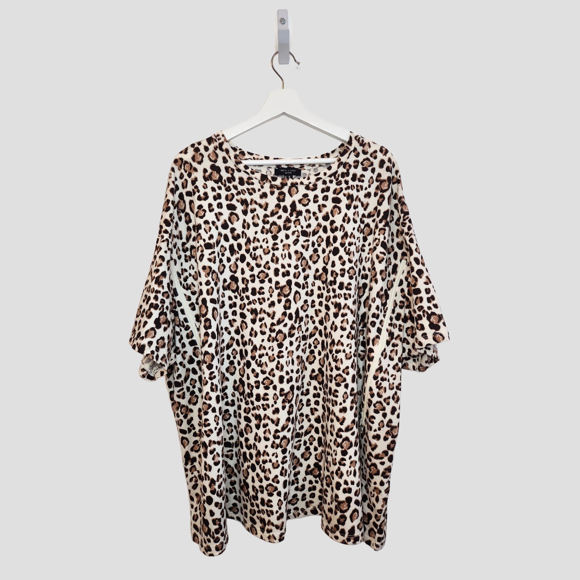 The New Look Upcycled Breastfeeding & Pumping Cream Leopard t-shirt UK26 (100290) features a loose fit and short sleeves, crafted from preloved clothing in a brown and black leopard print, shown on a white hanger against a light gray background.