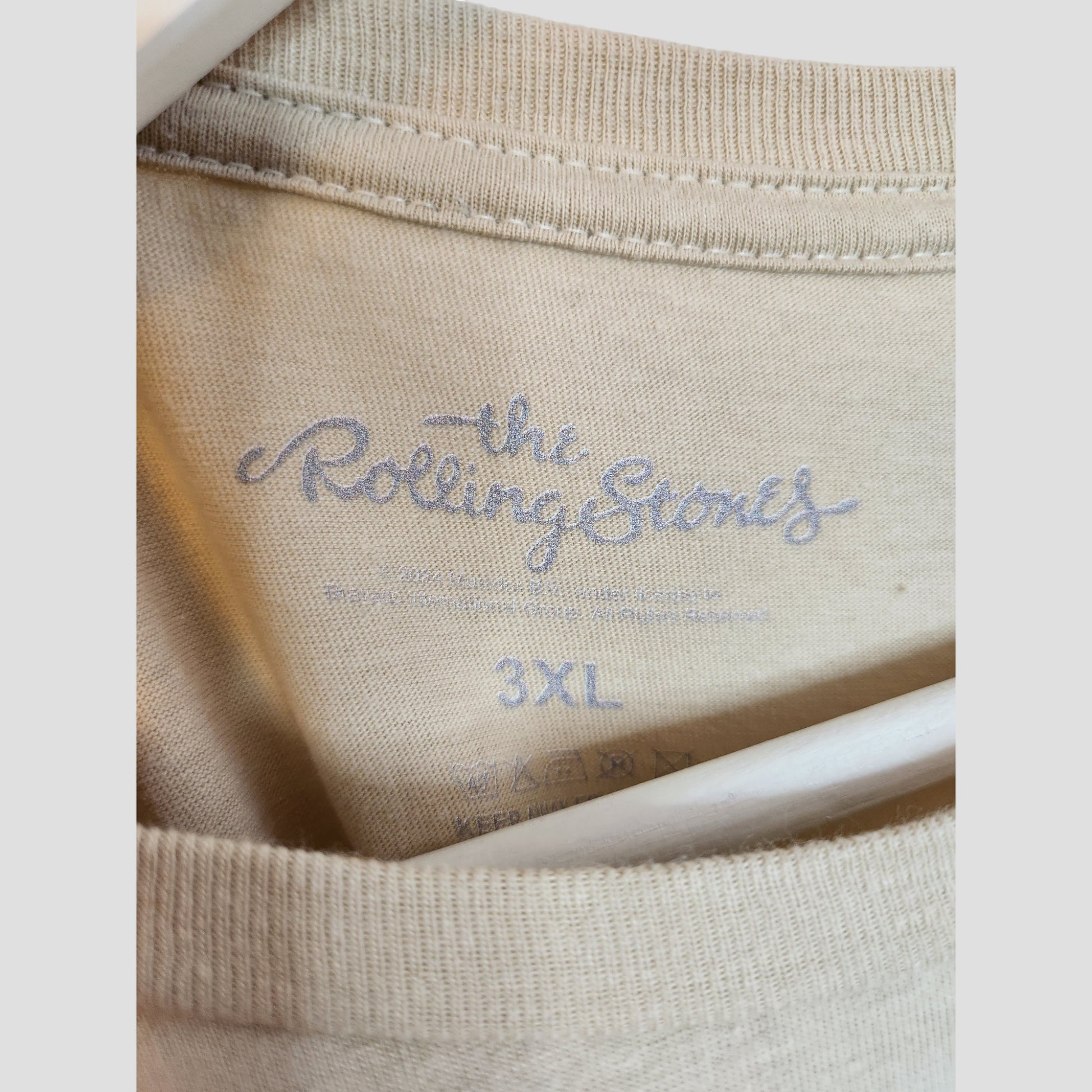Close-up of the Upcycled Breastfeeding & Pumping Beige Leopard The Rolling Stones T-shirt 3XL, showing the logo printed inside the collar and care symbols. Part of our eco-friendly maternity collection by The Rolling Stones.