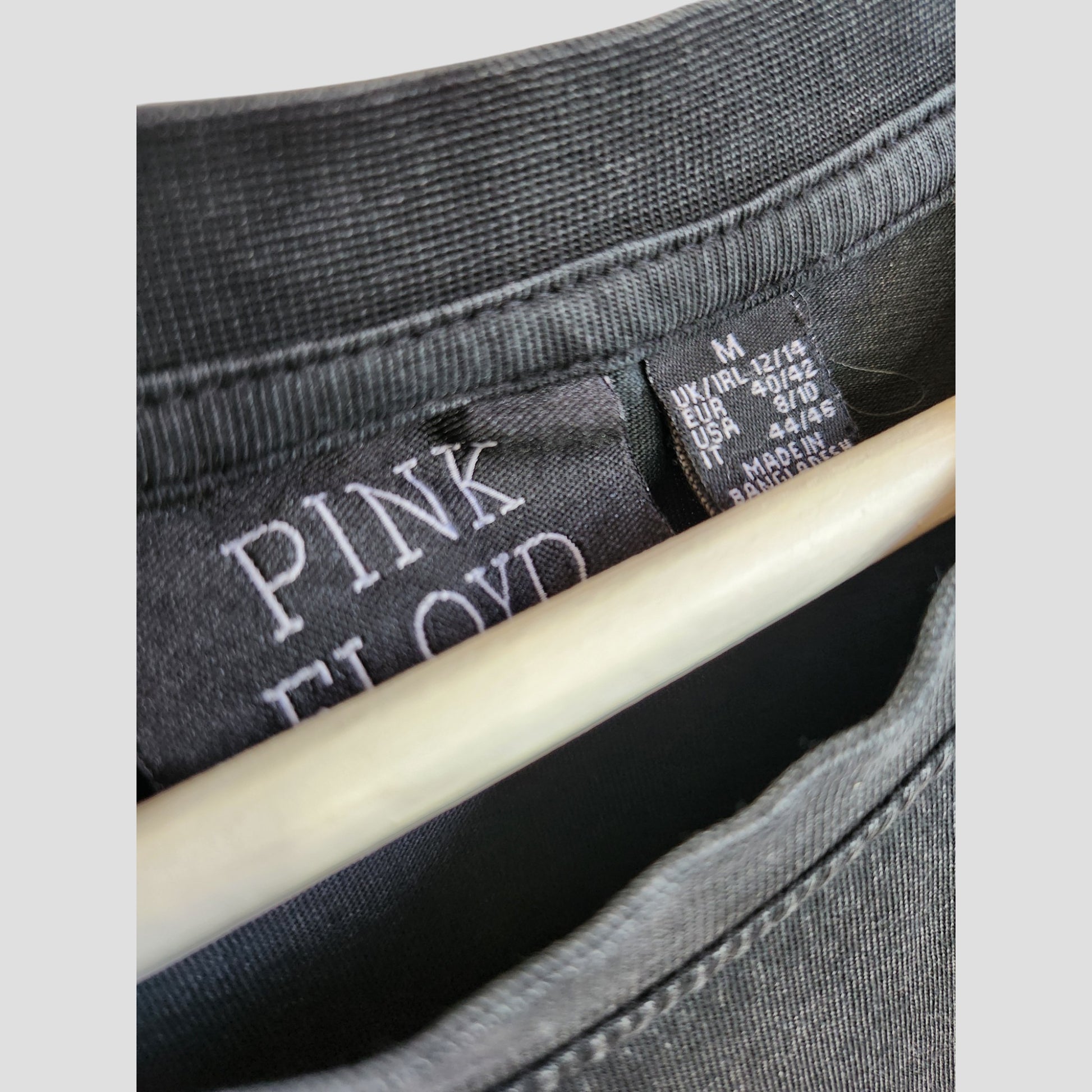 Close-up of the collar on a Primark Upcycled Breastfeeding & Pumping Grey Pink Floyd Band Oversized t-shirt dress (UK12/14), highlighting the embroidered PINK FLOYD label and size tag—sustainable preloved fashion with unique character.