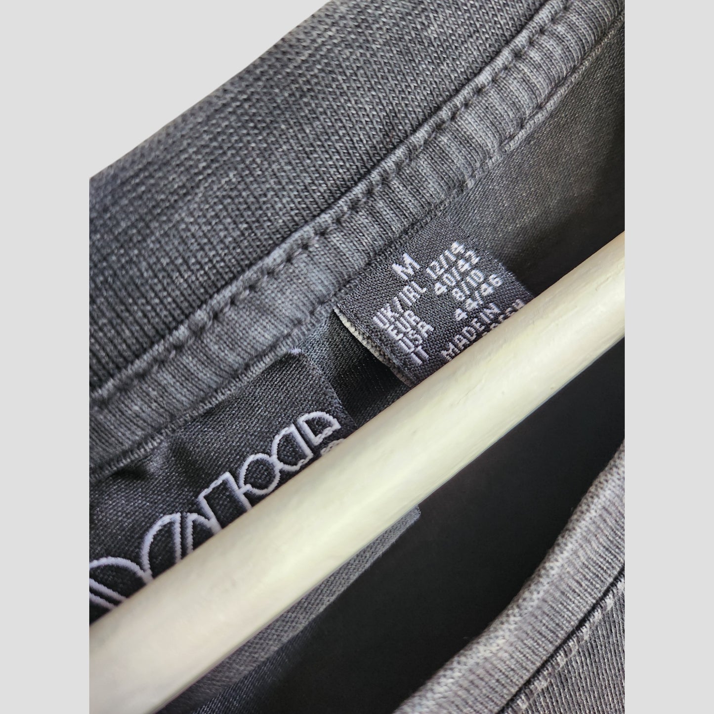 Close-up of a Primark tag on an Upcycled Breastfeeding & Pumping The Doors Band Oversized t-shirt dress (M/UK12/14), showing size, care info, and laundry symbols. Part of our eco-friendly preloved collection.