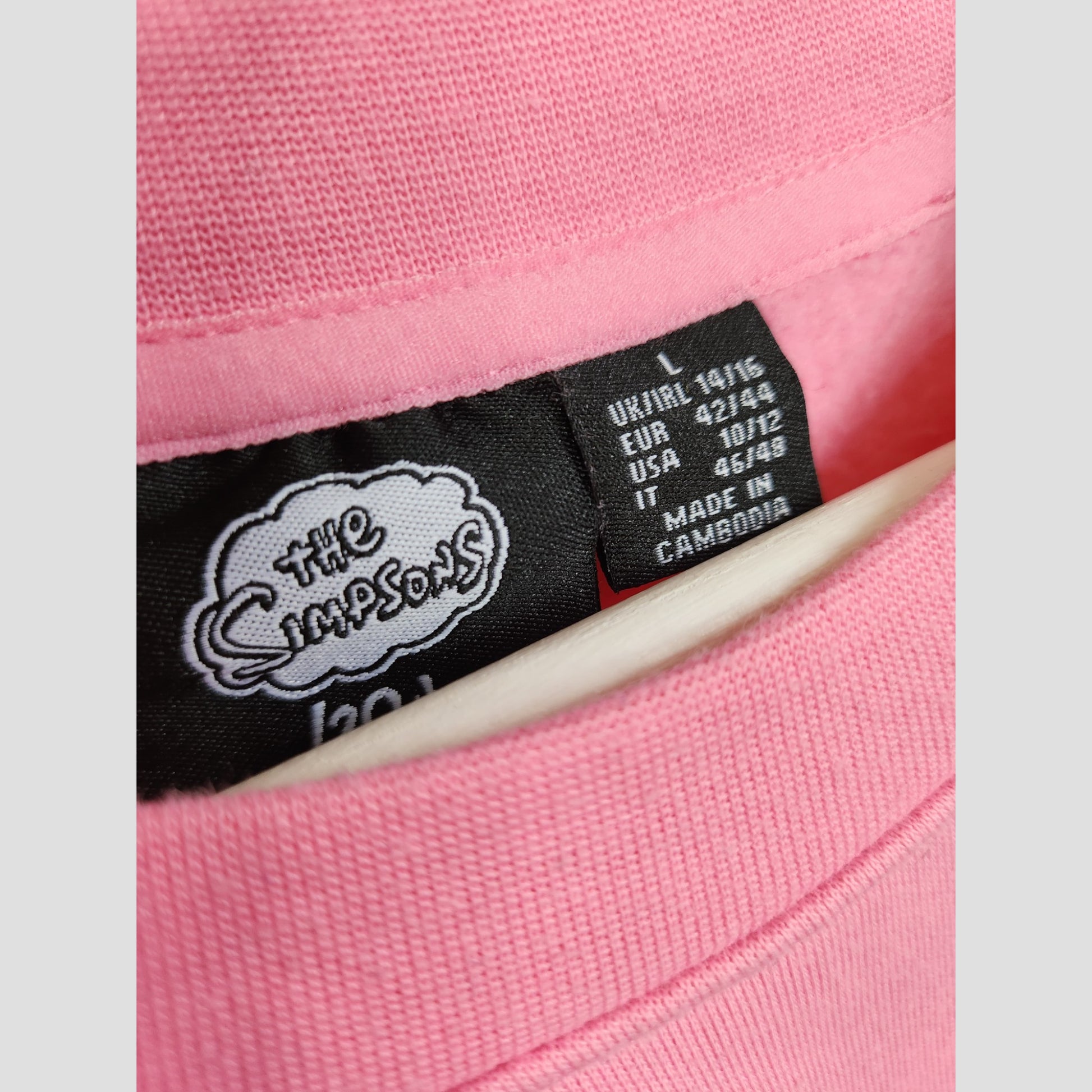 Close-up of the Upcycled Breastfeeding & Pumping Pink Lisa Simpson Sweatshirt by Primark, featuring a black The Simpsons label and white regional size tag showing UK14/16 (L), made in Cambodia.