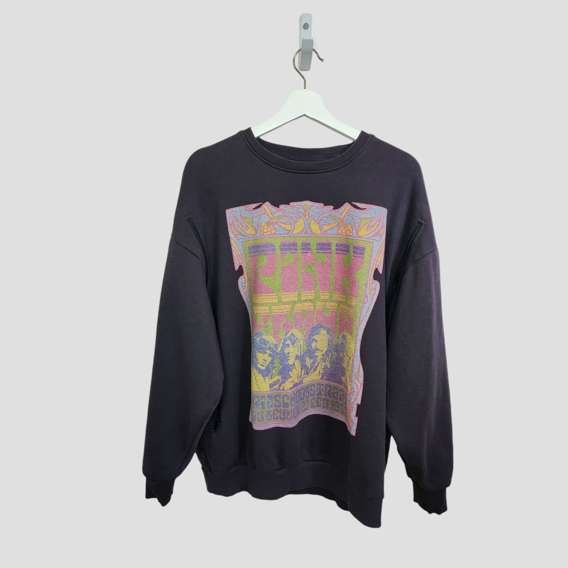 A grey Upcycled Primark Pink Floyd Band Sweatshirt (size S, UK10/12) for breastfeeding & pumping hangs on a white hanger, featuring a colorful graphic and bold text, made from preloved clothing against a light gray background.