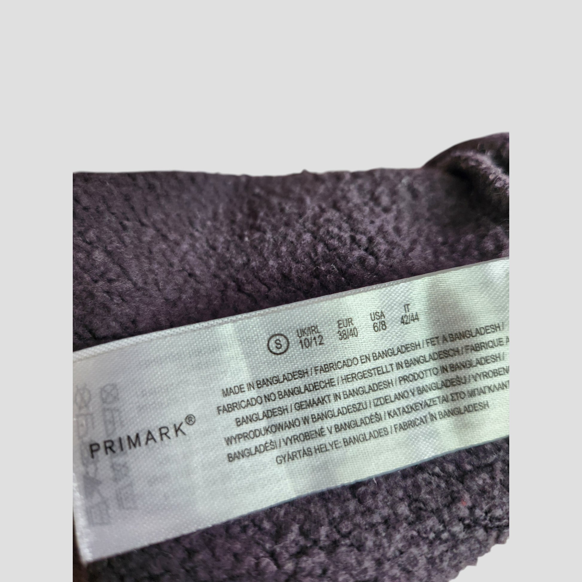 A close-up of a Primark clothing label on an upcycled grey Pink Floyd Band Nursing & Pumping Sweatshirt (Size S, UK 10/12), made in Bangladesh—affordable eco fashion for fans of preloved clothing.