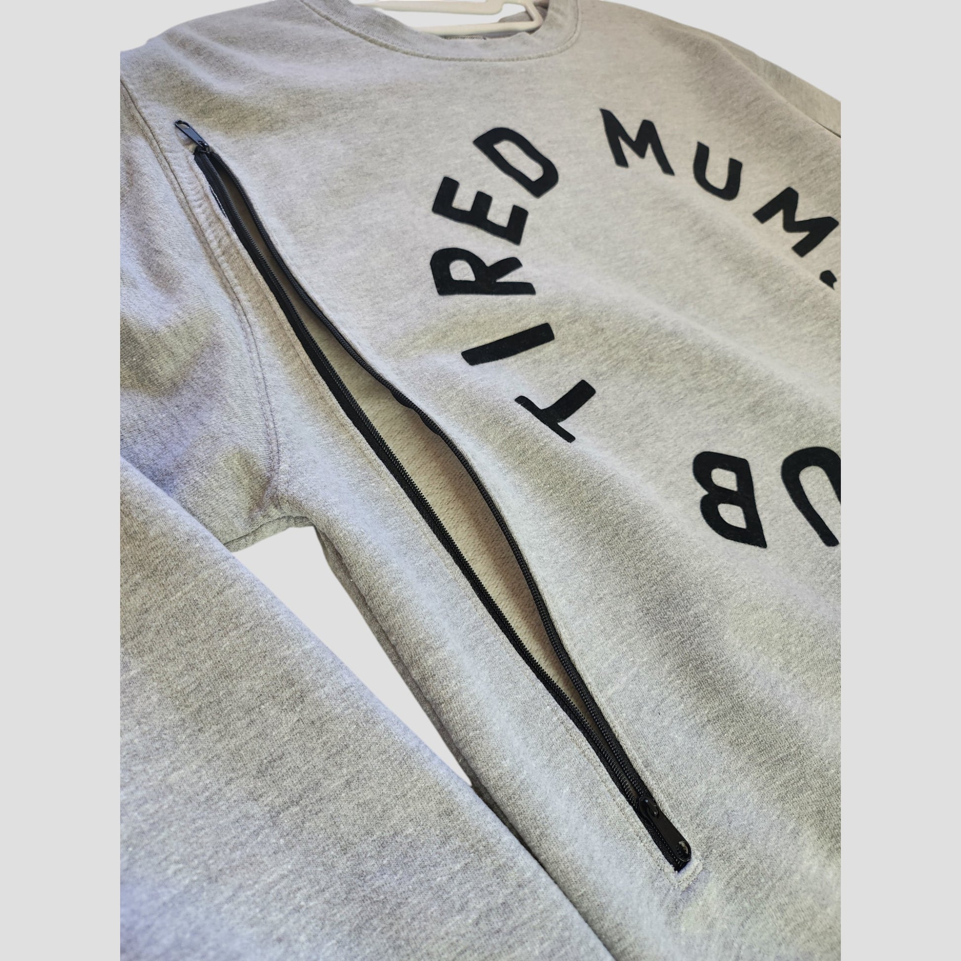 The Momma Makes Upcycled Breastfeeding & Pumping Tired Mums Club Sweatshirt M (100190) features "TIRED MUM CLUB" in bold black letters and a diagonal zipper—perfect for stylish, sustainable nursing.