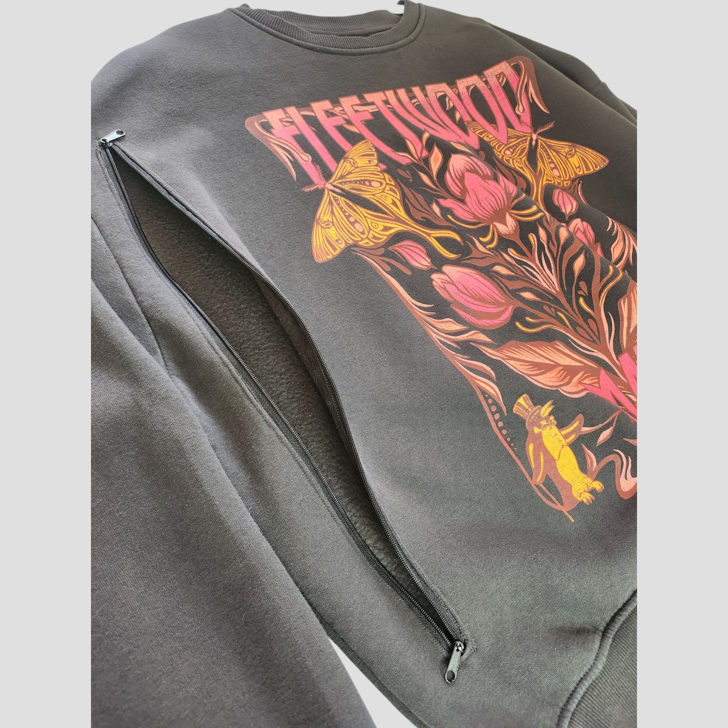 The Primark Upcycled Breastfeeding & Pumping Dark Grey Fleetwood Mac Floral Band Sweatshirt (L, UK14/16) features a colorful floral design and diagonal zipper, crafted from upcycled materials for eco-friendly, stylish nursing comfort.