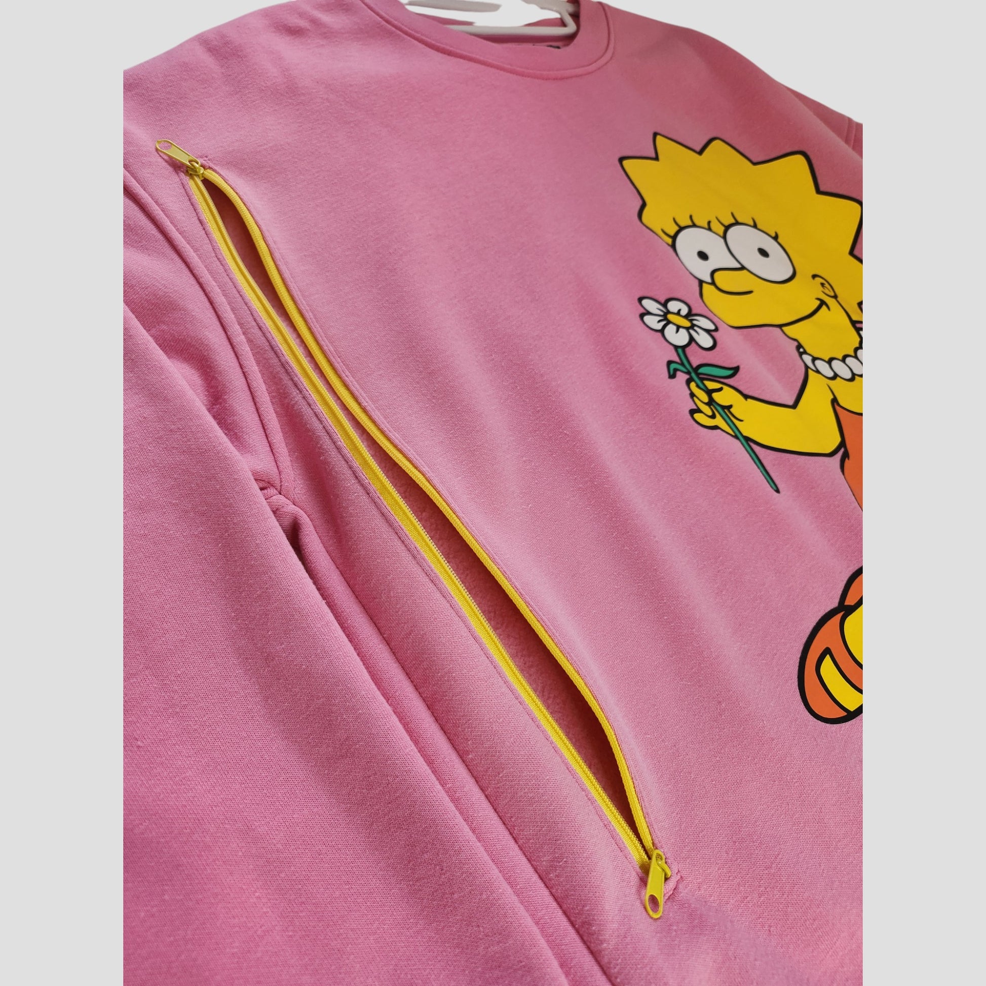 The Upcycled Primark Pink Lisa Simpson Nursing Sweatshirt (L, UK14/16) features a playful design and diagonal yellow zipper—perfect for stylish, eco-conscious breastfeeding moms seeking affordable fashion.