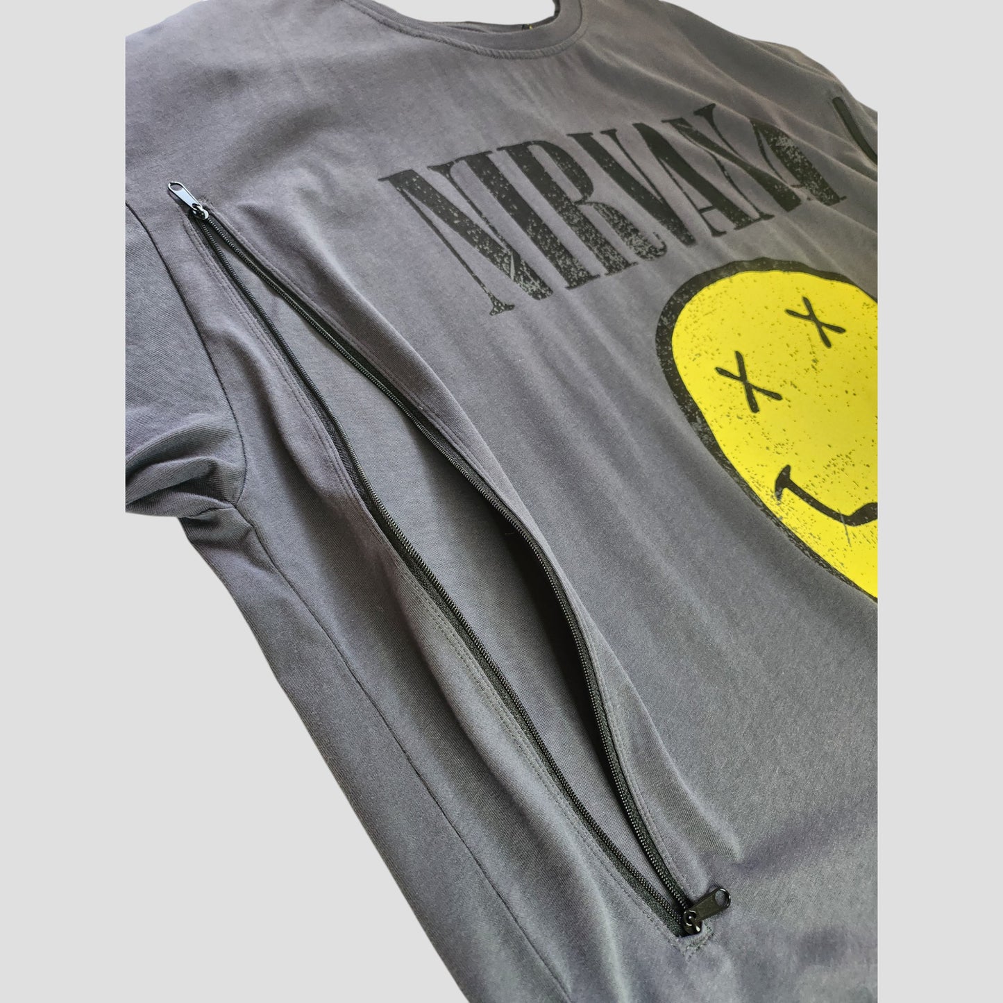 Primark's Upcycled Breastfeeding & Pumping Grey Nirvana Yellow Smile Band t-shirt (XL UK18/20) features a smiley face with X eyes, a large diagonal zipper, and is crafted from preloved clothing for eco-friendly, affordable style.