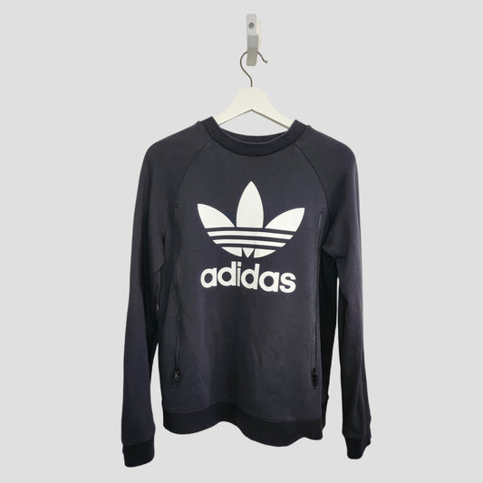 A black upcycled Adidas breastfeeding & pumping sweatshirt UK14 (100271) with long sleeves and a white trefoil logo on the front, hangs on a white hanger against a plain light gray background.