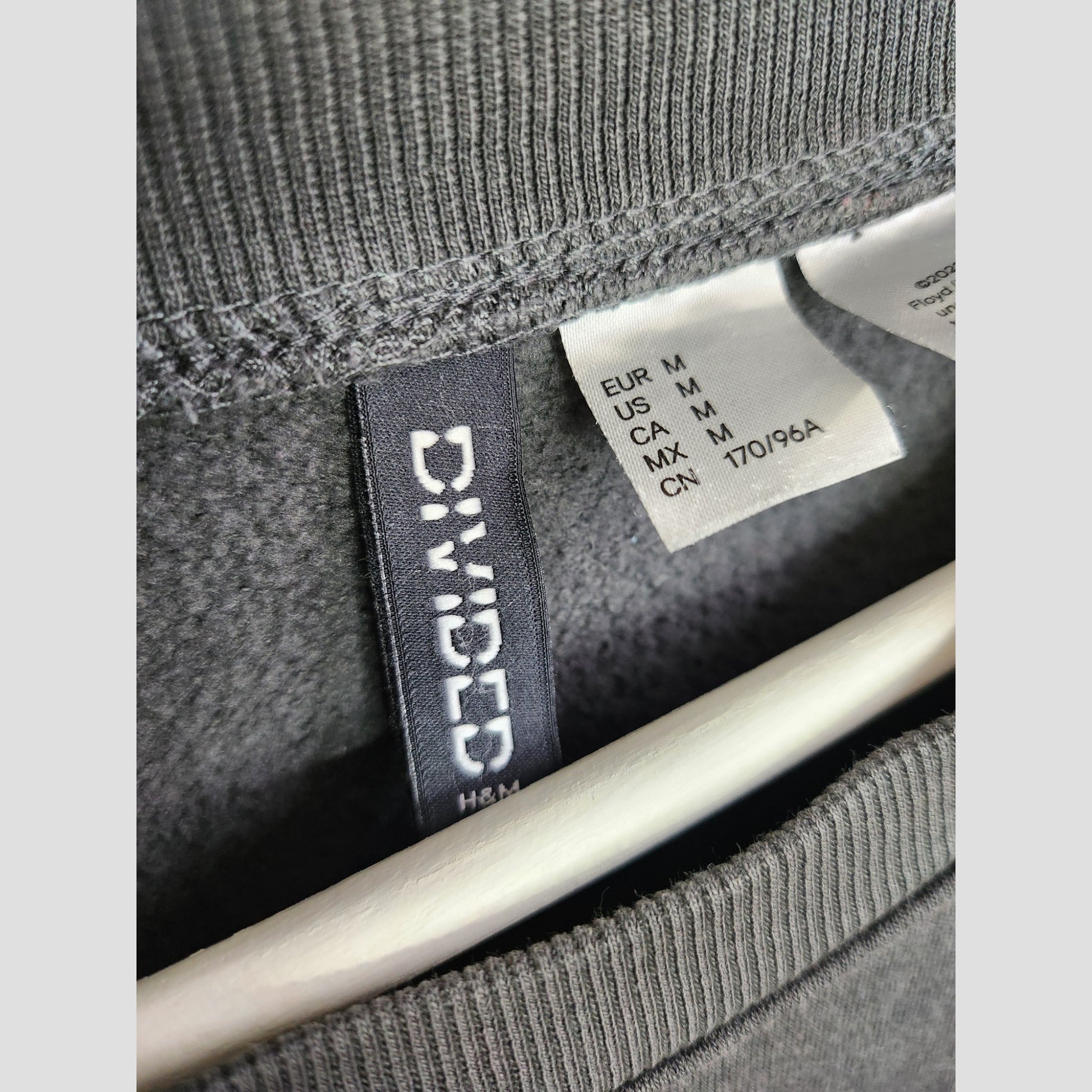 Close-up of a gray Upcycled Breastfeeding & Pumping Pink Floyd Oversized Band Sweatshirt (M, UK12/14) by Primark, on hanger—an affordable eco choice for stylish and sustainable nursing wear.