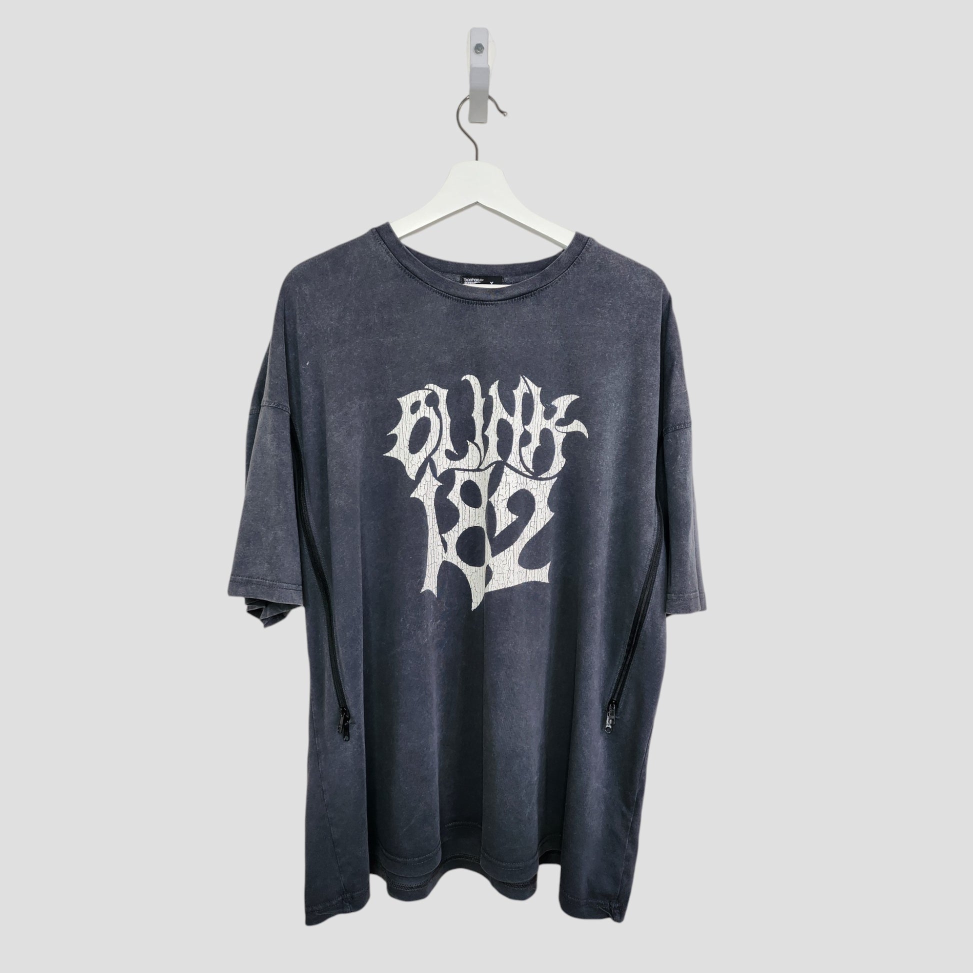 The Boohoo Upcycled Breastfeeding & Pumping Blink 182 Band T-shirt (M, 100324) is a black oversized tee with bold white BLINK 182 text on the front, made from repurposed nursing wear and shown hanging on a white hanger against a light gray background.