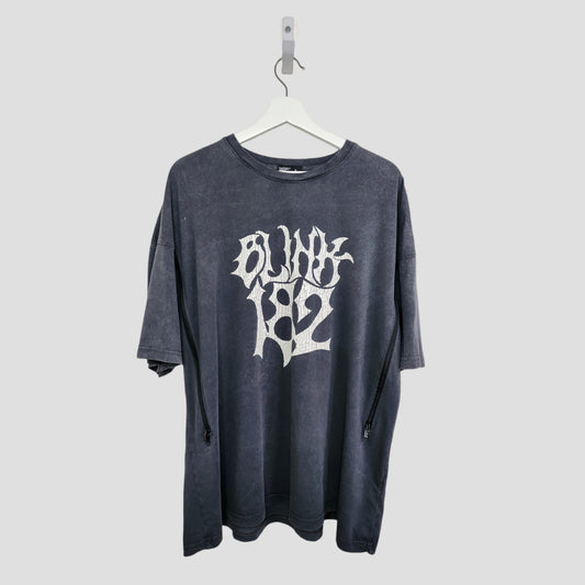 The Boohoo Upcycled Breastfeeding & Pumping Blink 182 Band T-shirt (M, 100324) is a black oversized tee with bold white BLINK 182 text on the front, made from repurposed nursing wear and shown hanging on a white hanger against a light gray background.