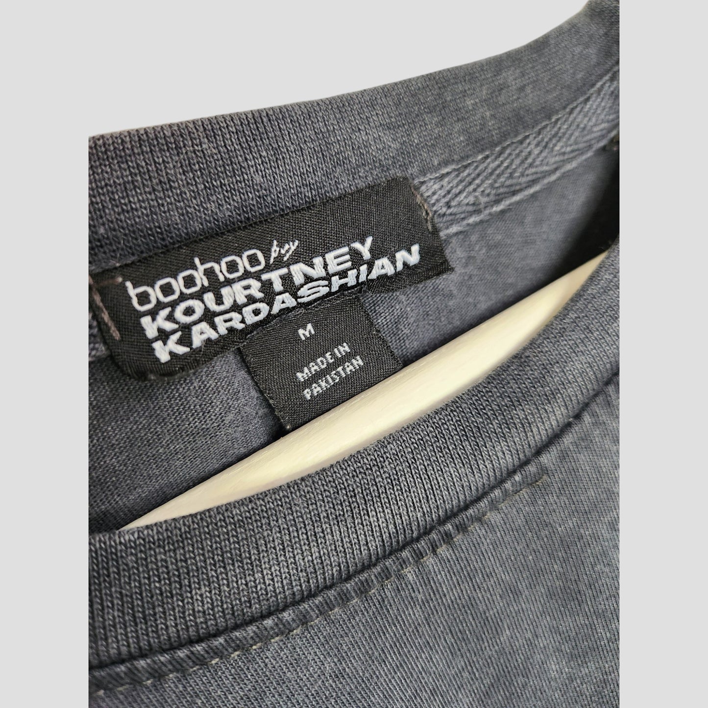 Close-up of a black Boohoo label on a dark Upcycled Breastfeeding & Pumping Blink 182 Band t-shirt (M), with the tag reading size M and Made in Pakistan.