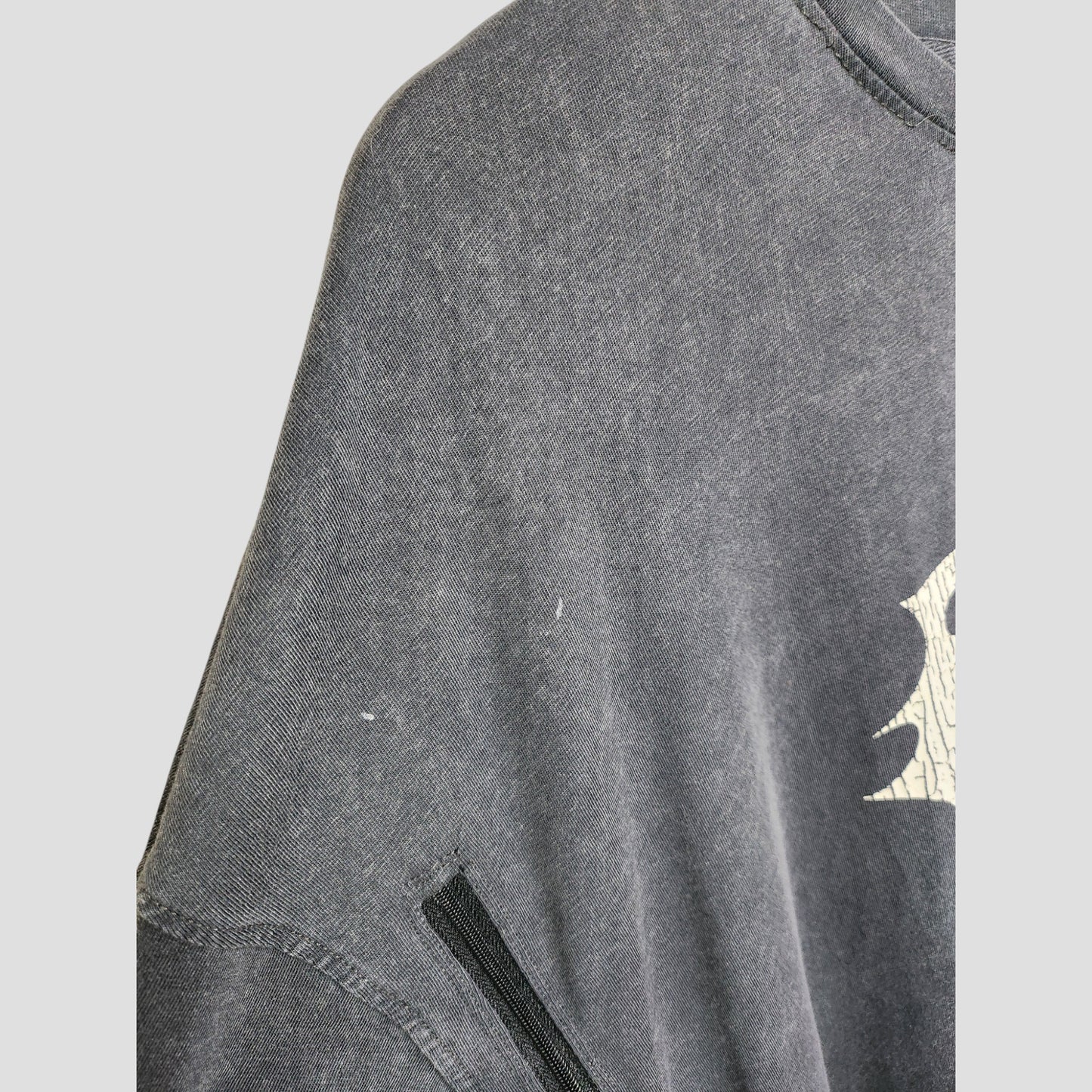 A close-up of a faded Boohoo Upcycled Breastfeeding & Pumping Blink 182 Band t-shirt (M) shows a partial white graphic, visible black seam, slight discoloration, and small white marks. Originally eco-friendly maternity clothing.