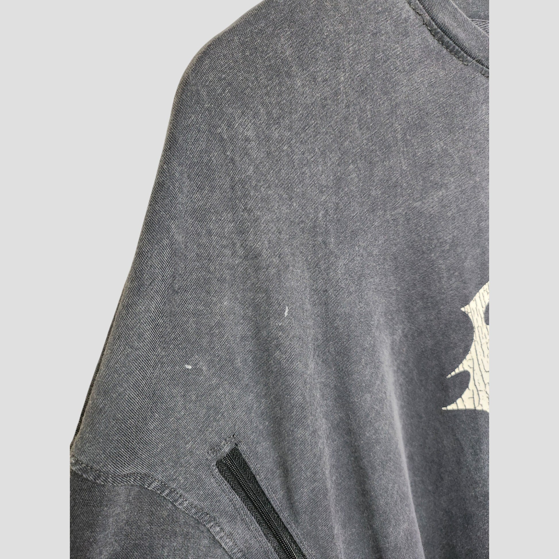 A close-up of a faded Boohoo Upcycled Breastfeeding & Pumping Blink 182 Band t-shirt (M) shows a partial white graphic, visible black seam, slight discoloration, and small white marks. Originally eco-friendly maternity clothing.